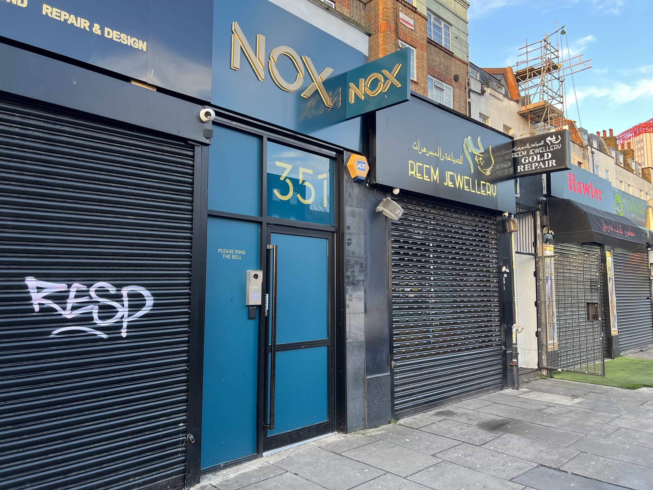 The blue entrance door to NOX, Edgware Road with two shops either side