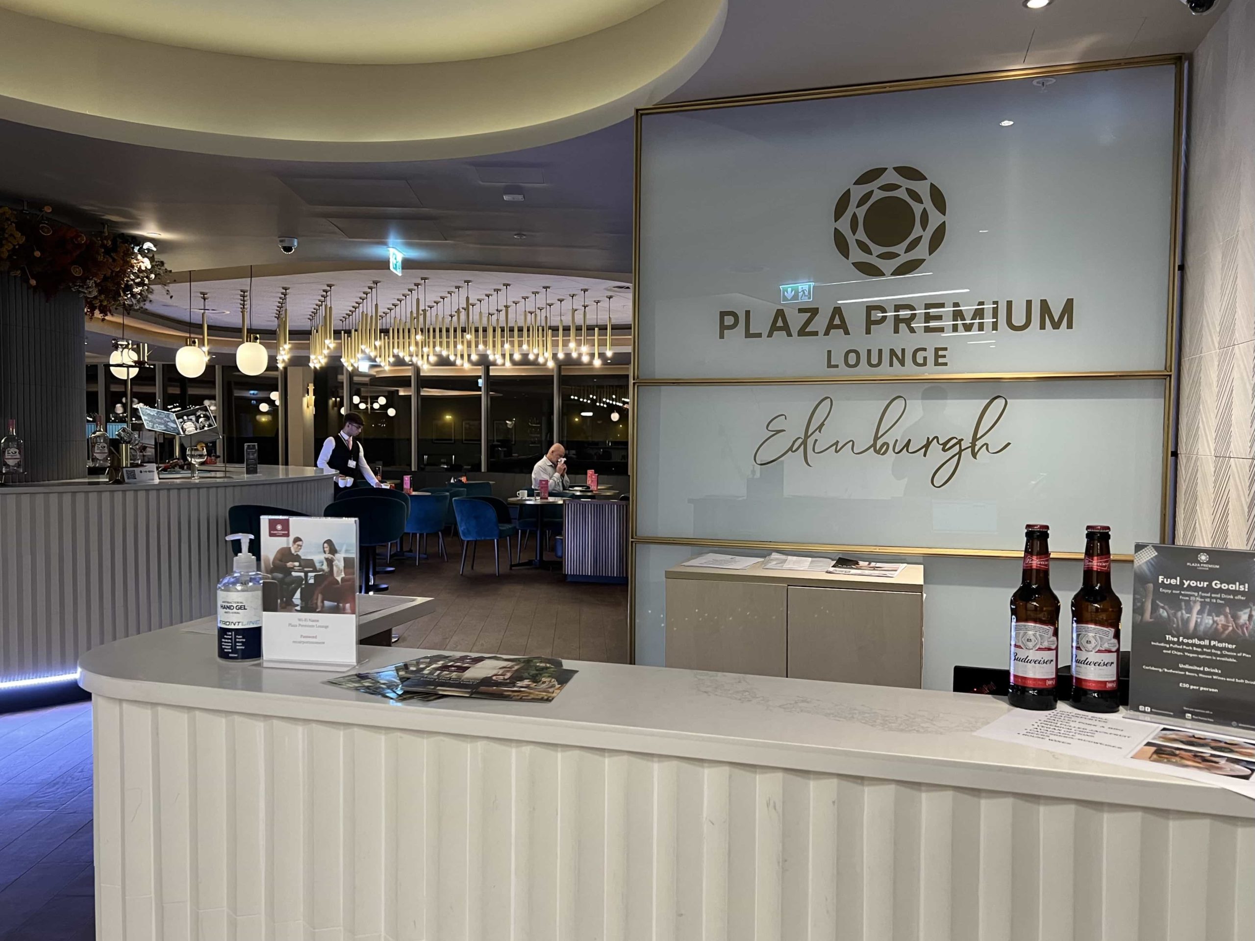 The reception desk in the Plaza Premium lounge at Edinburgh Airport, with the bar area visible to the left