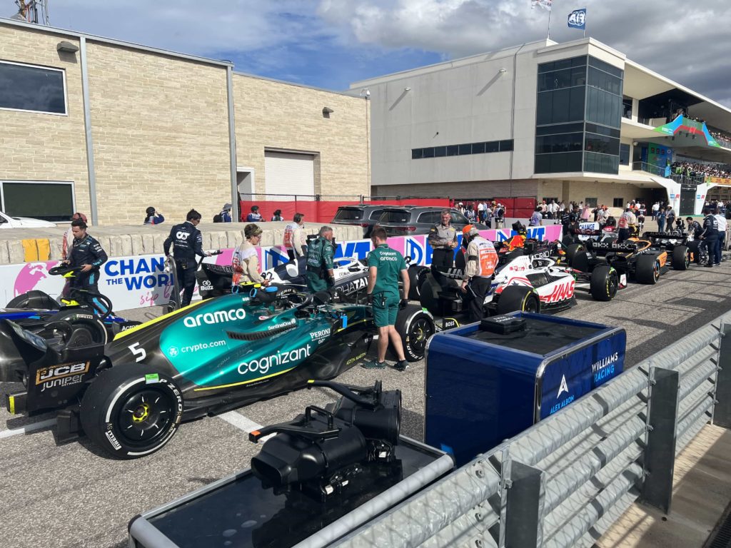 A lineup of F1 cars, being wheeled back into the pit lane after a race
