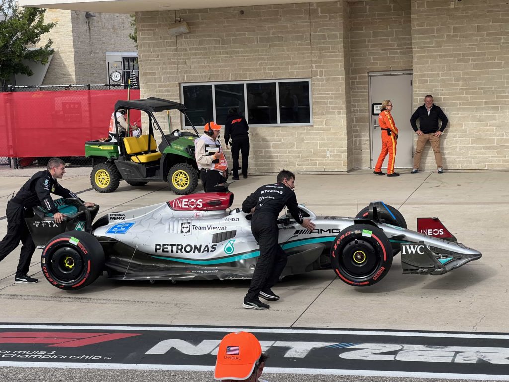 A Mercedes F1 car, being wheeled by mechanics into the pit lane after a race