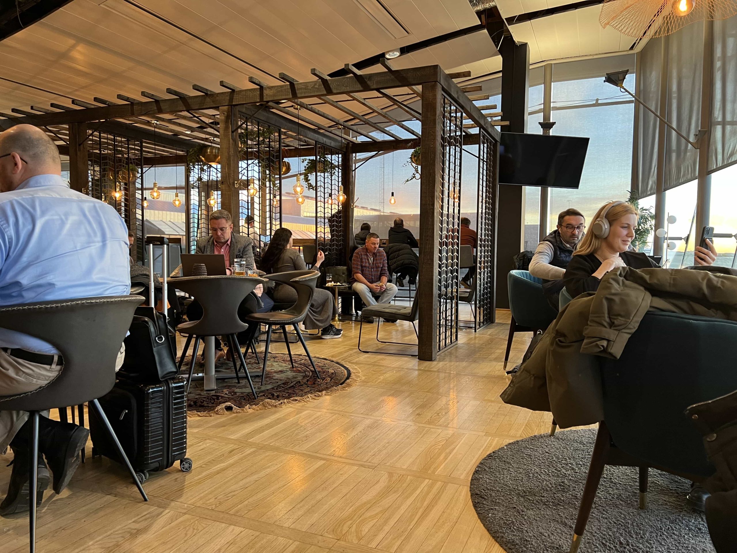 An indoor pergola sits within the middle of an airport lounge, with seating around an underneath