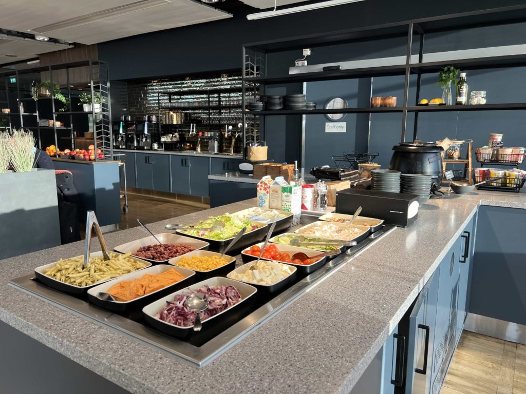 A sunken salad bar area, with bowls of ingredients, utensils, and other food items in the background 