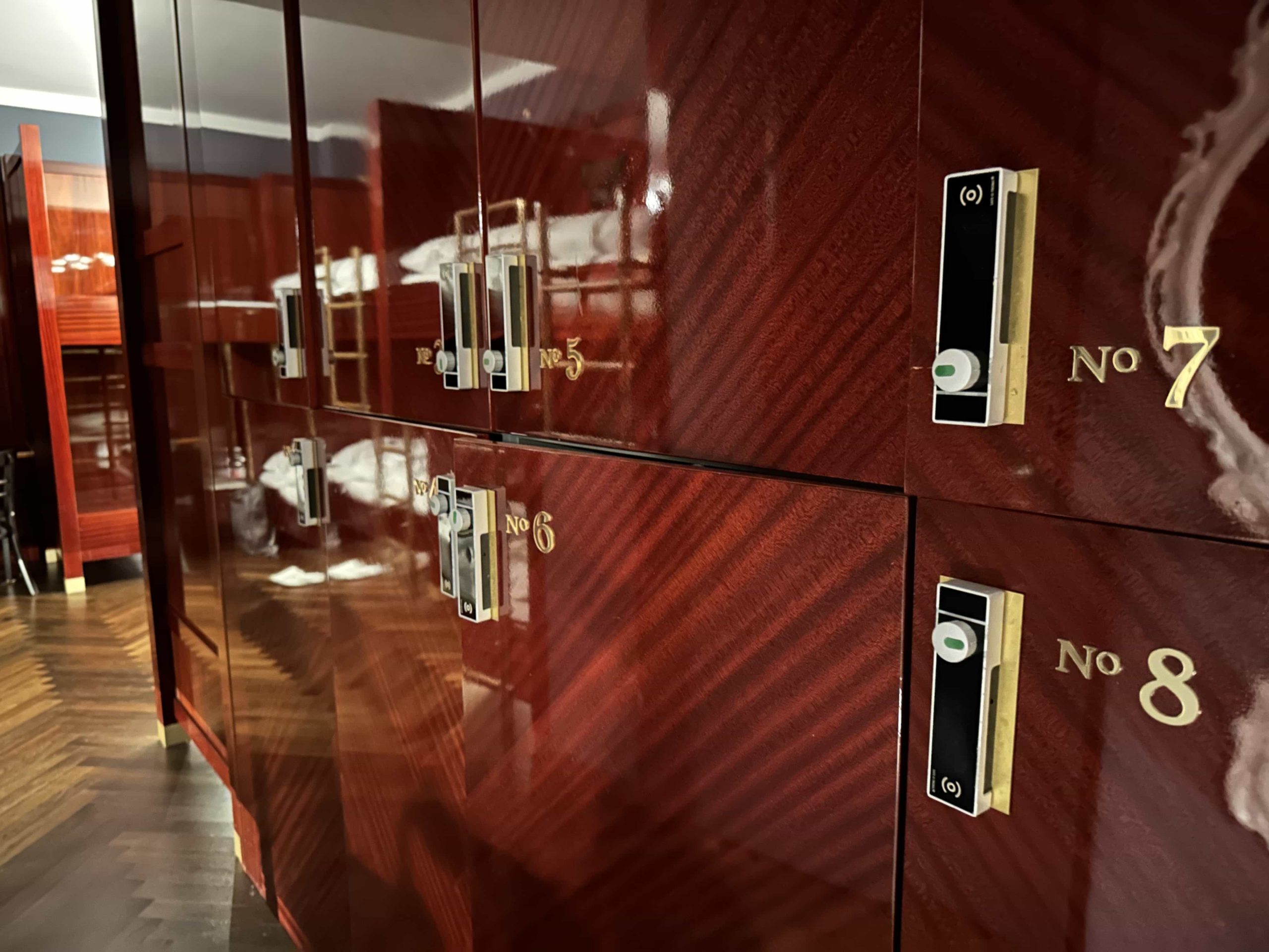 A line of integrated lockers, clad in polished mahogany, within a dorm room