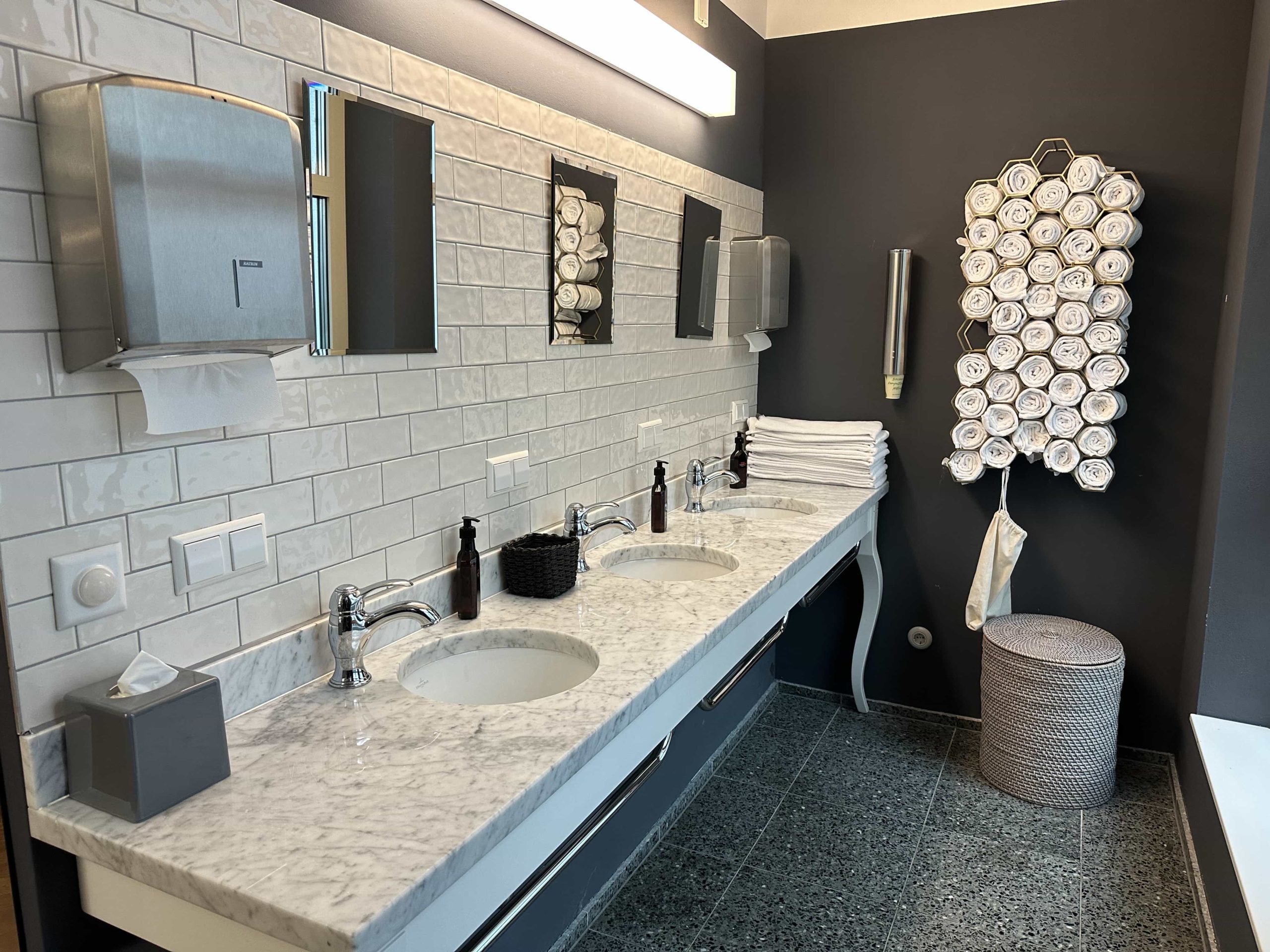 A sink area within a fitness centre, well-stocked with amenities and towels