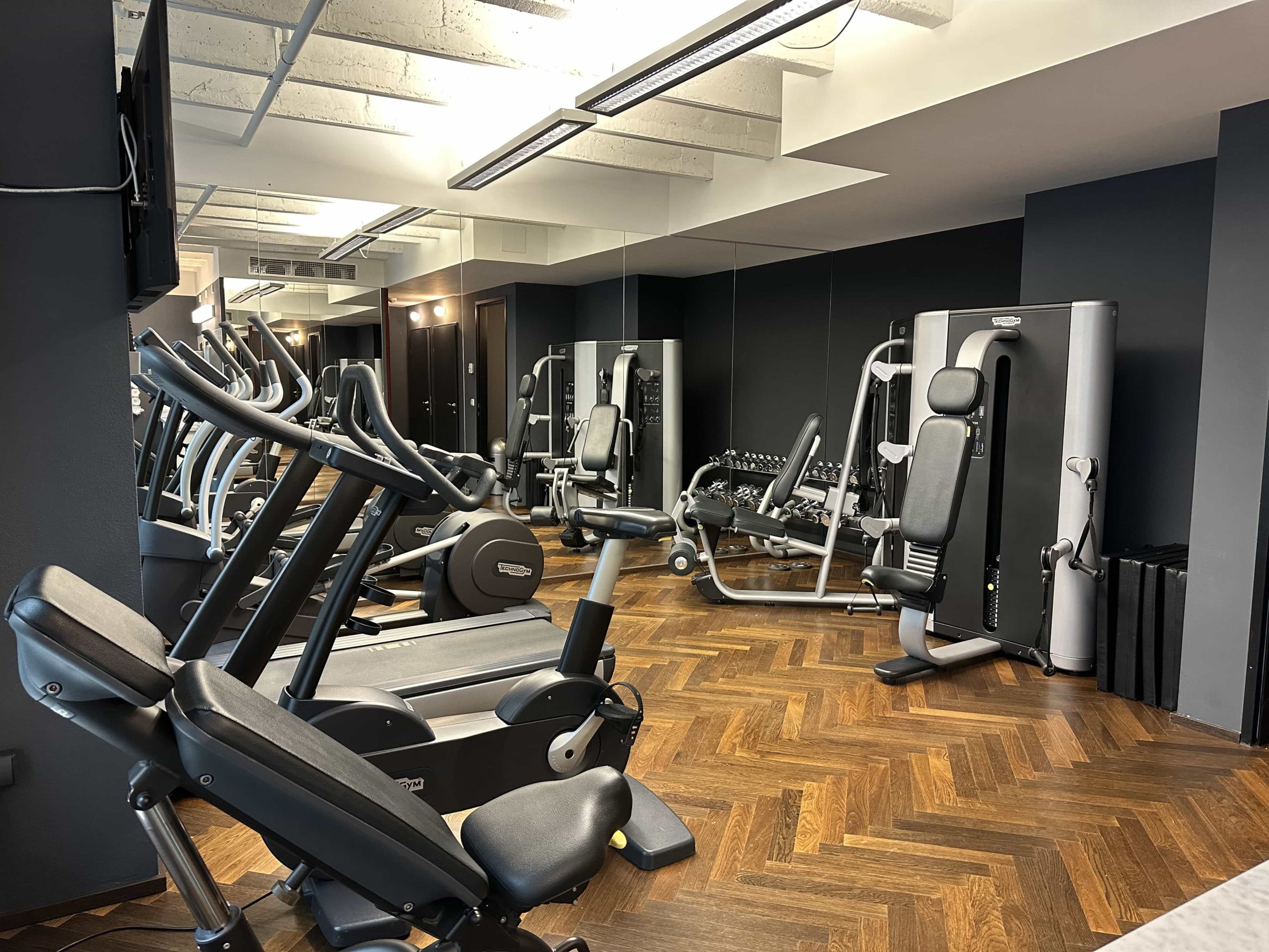 Gym equipment in a small room, including treadmill, elliptical, and weight machines