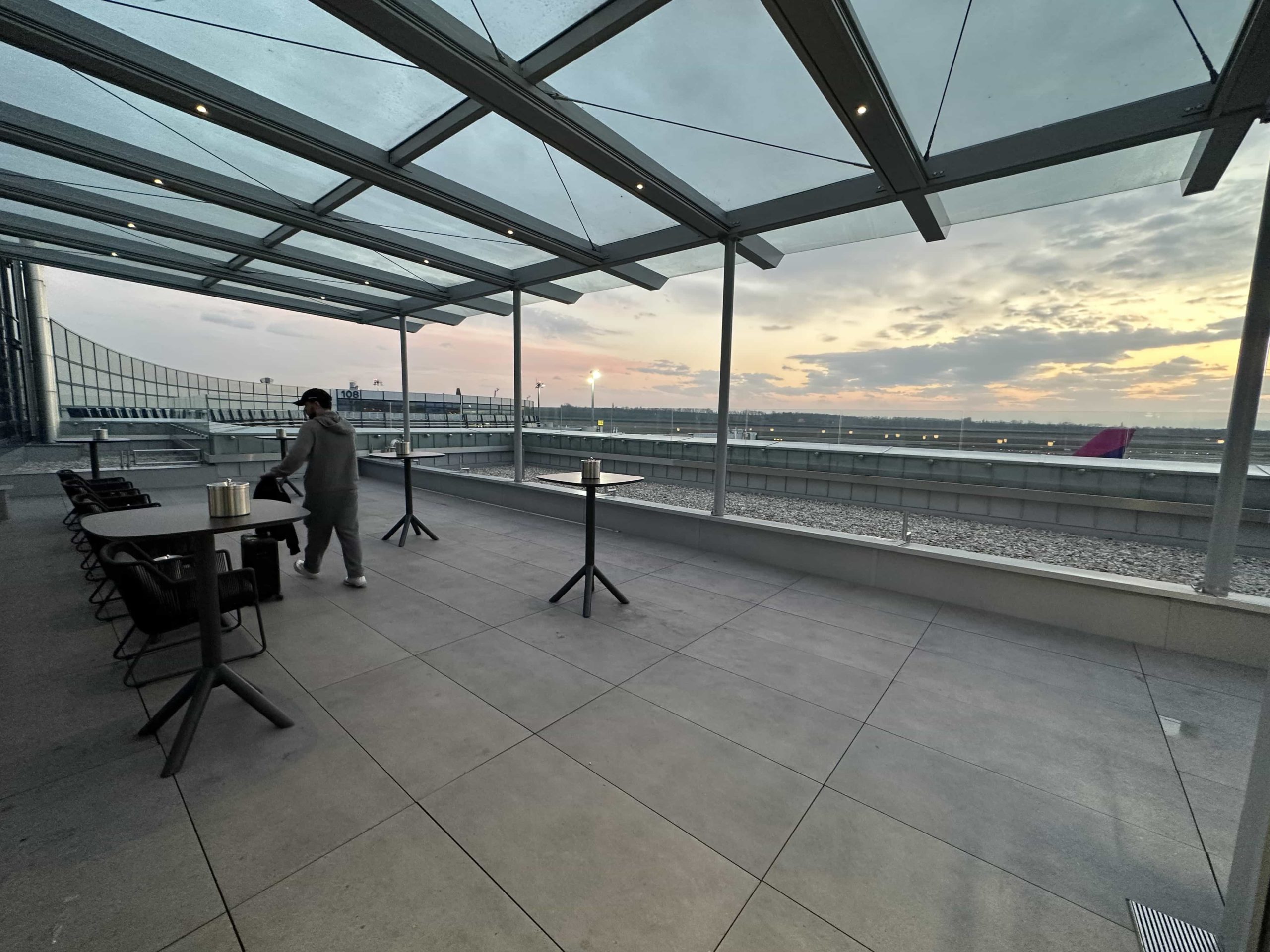 A basic, covered terrace, adjoining an airport lounge, with views over the airfield