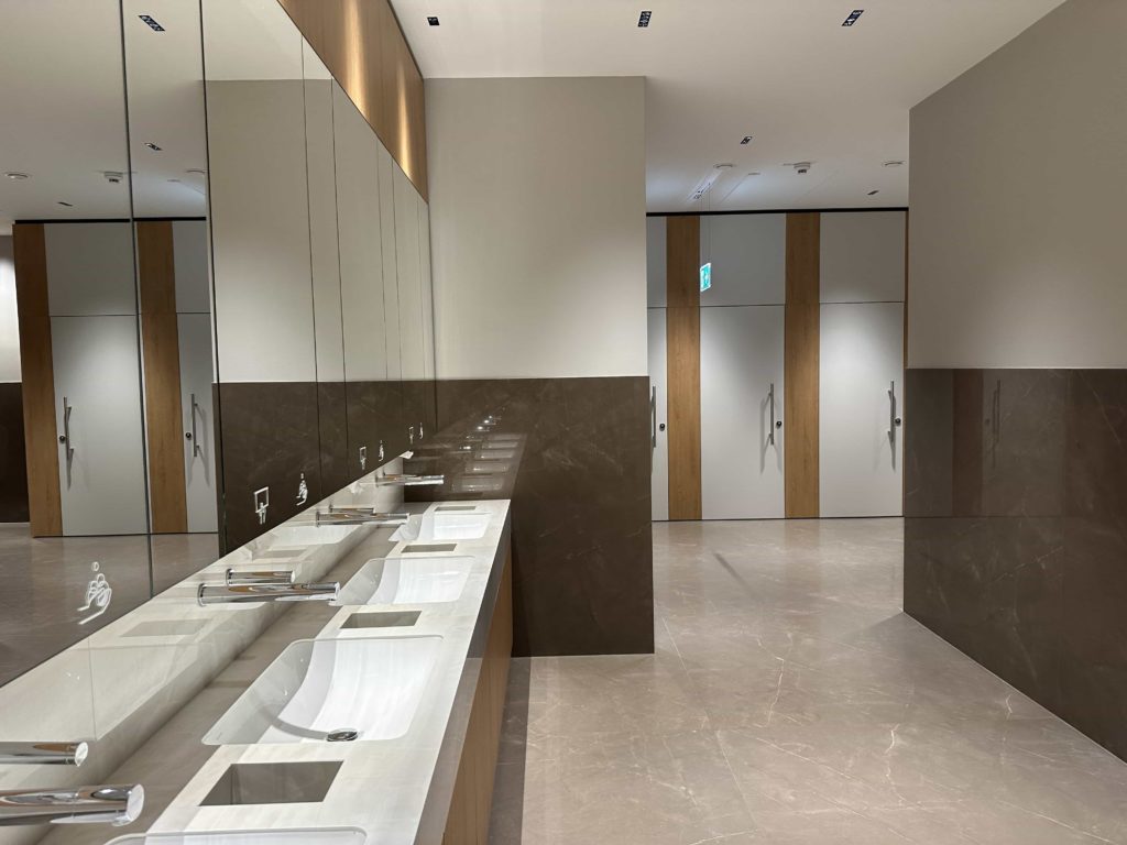 Clean and modern toilet facilities, with sinks on the left, and toilet stalls towards the back