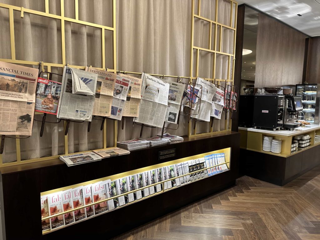 Newspapers hanging above a display cabinet containing magazines