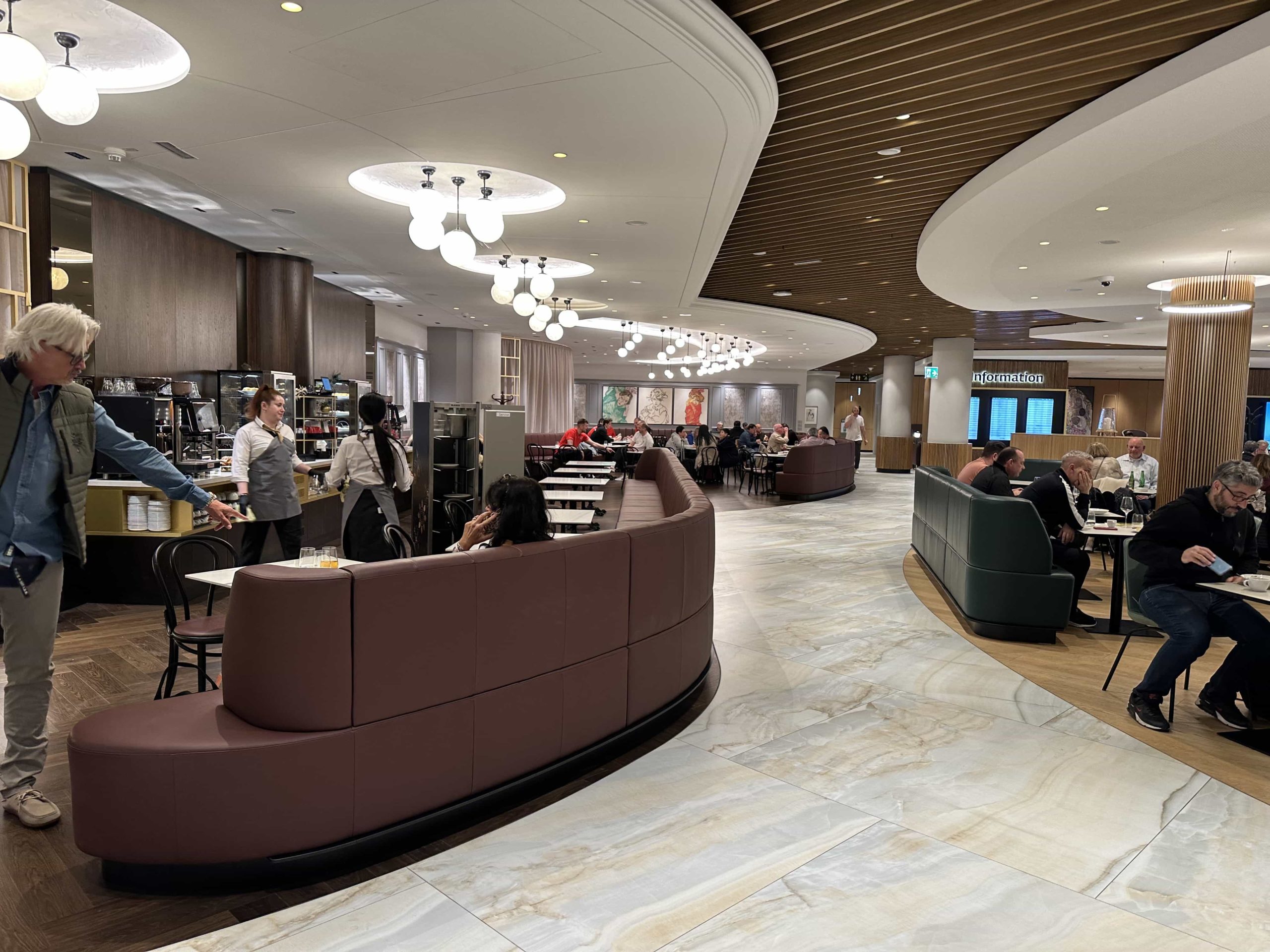 Restaurant seating in an airport lounge, with coffee machines and desserts on one side