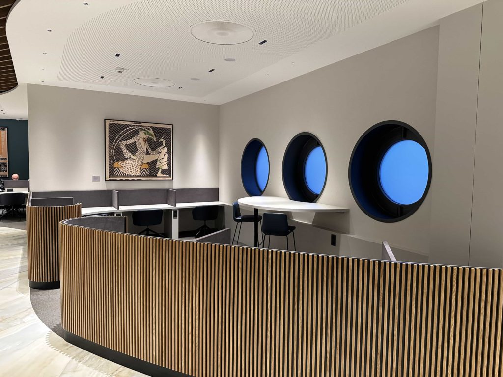 A nook of workstation desks, with porthole windows along with wall