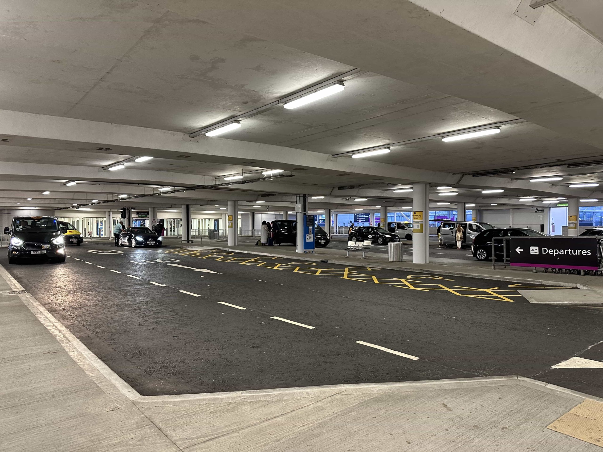 Lanes of parking bays with taxis and cars pulling up to drop people off