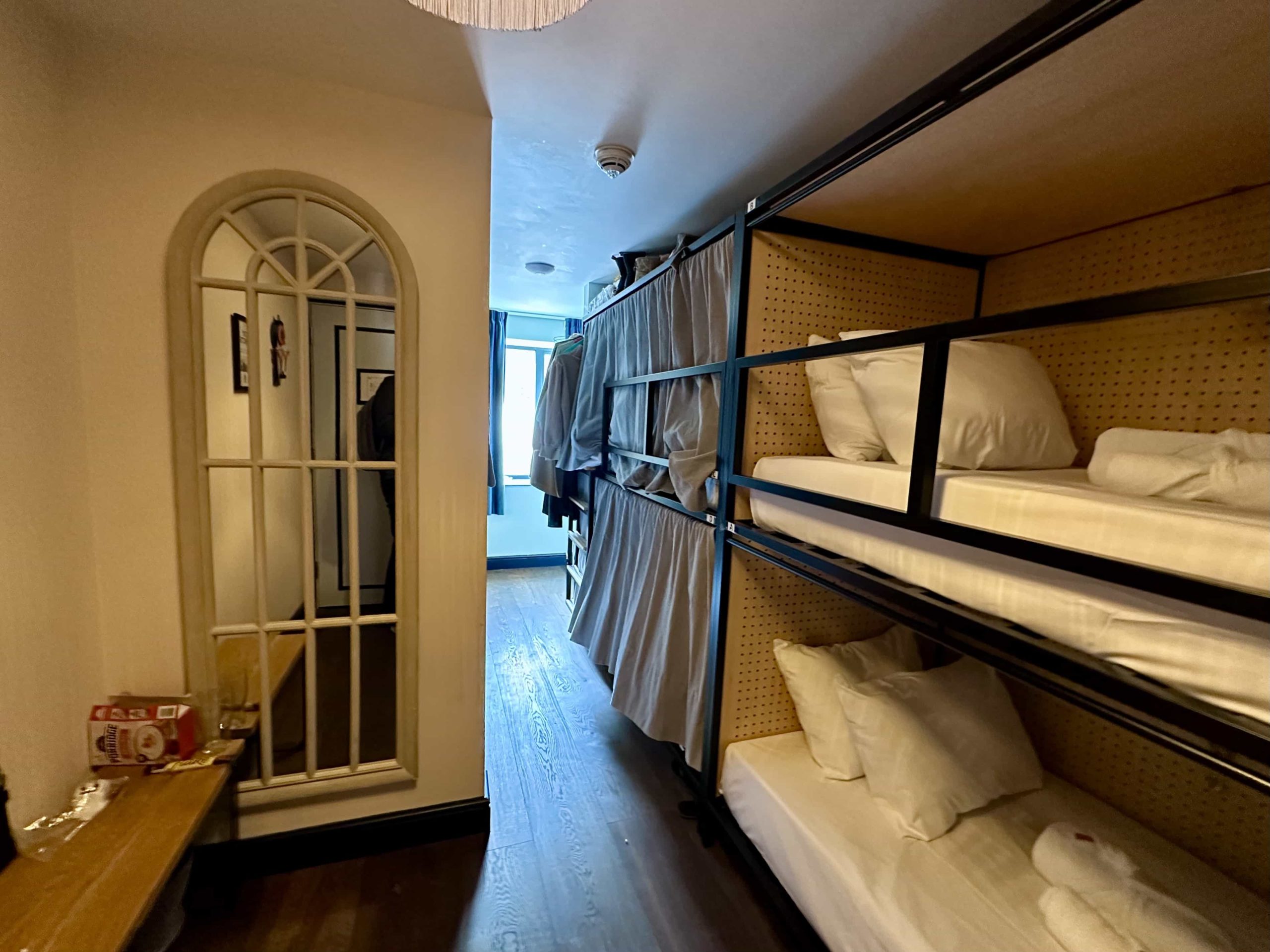 A dorm room with bunkbeds, each with privacy curtains