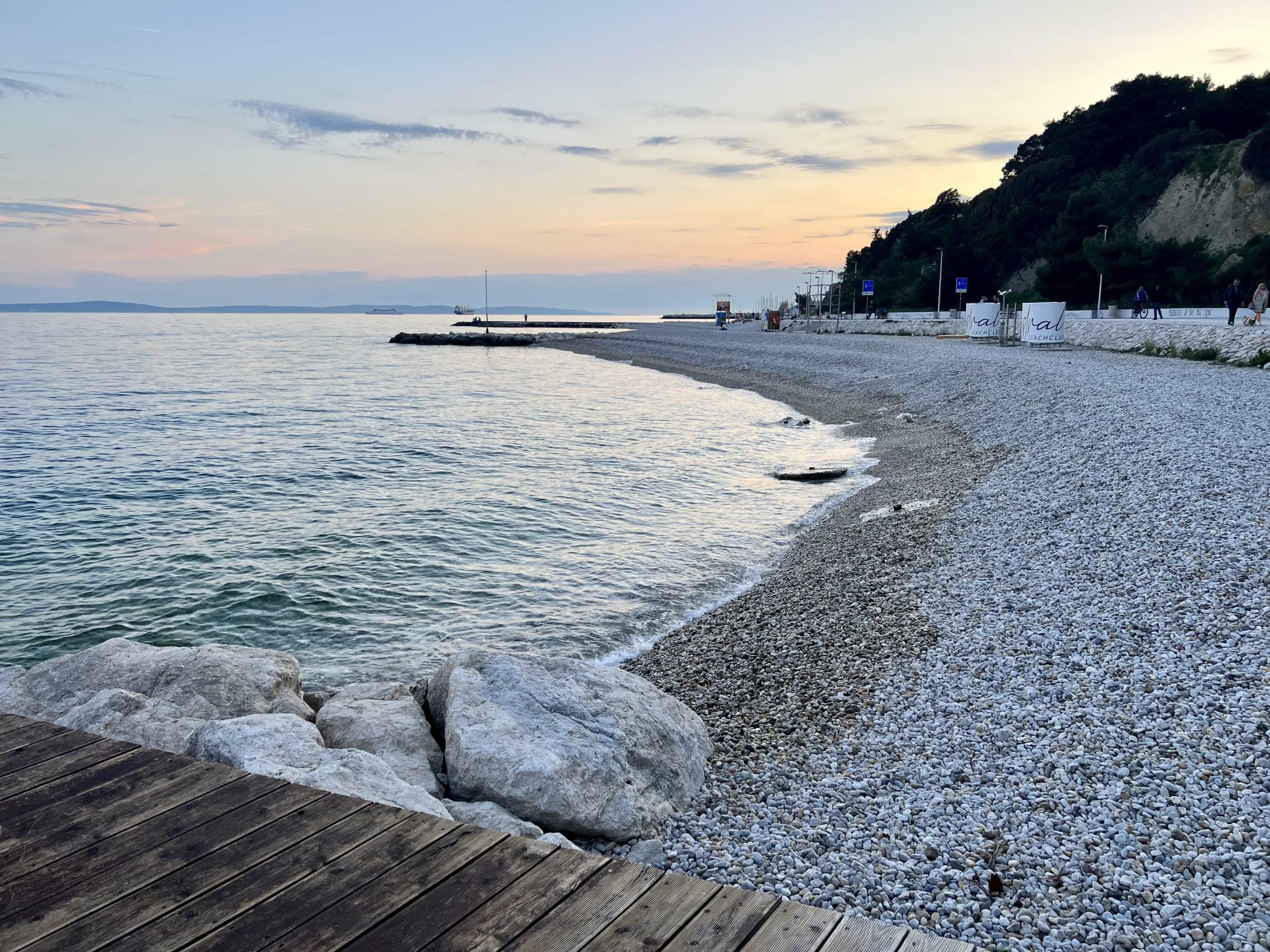 A pebbled beach, with turquoise water and a sunset