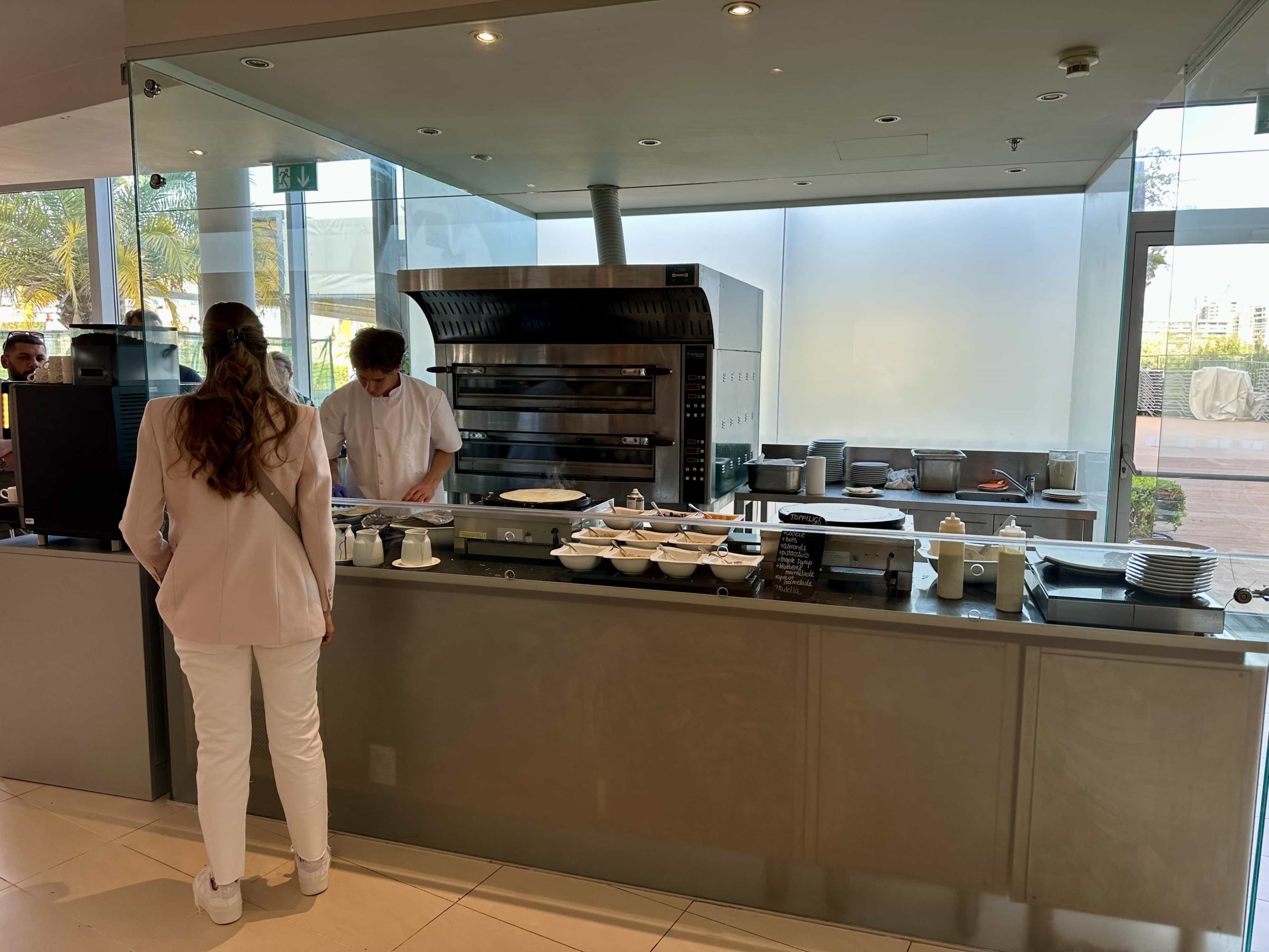 A chef making fresh pancakes and crepes at a station within a breakfast buffet setup