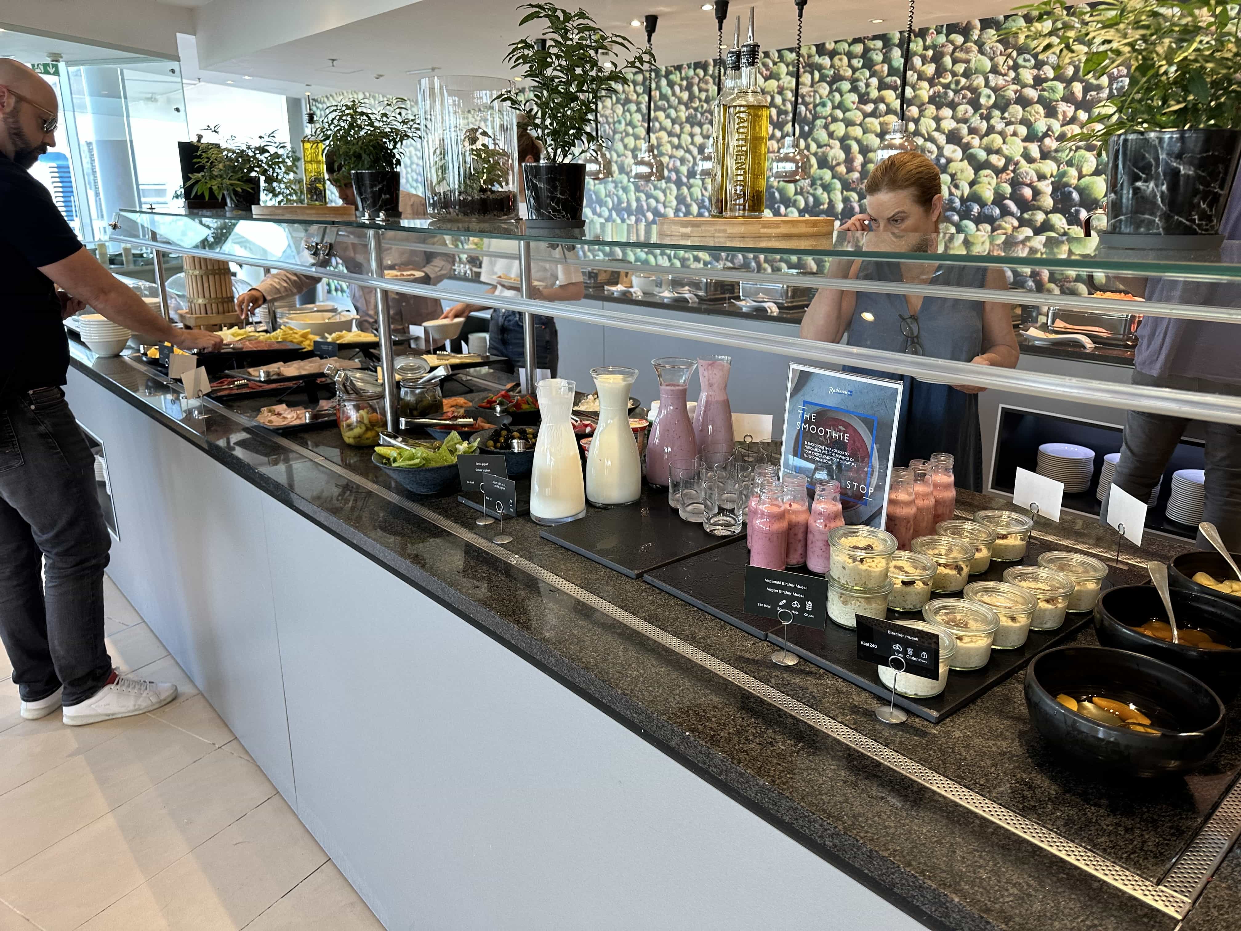 An assortment of continental foods at a buffet, including yogurts, smoothies, and fruit