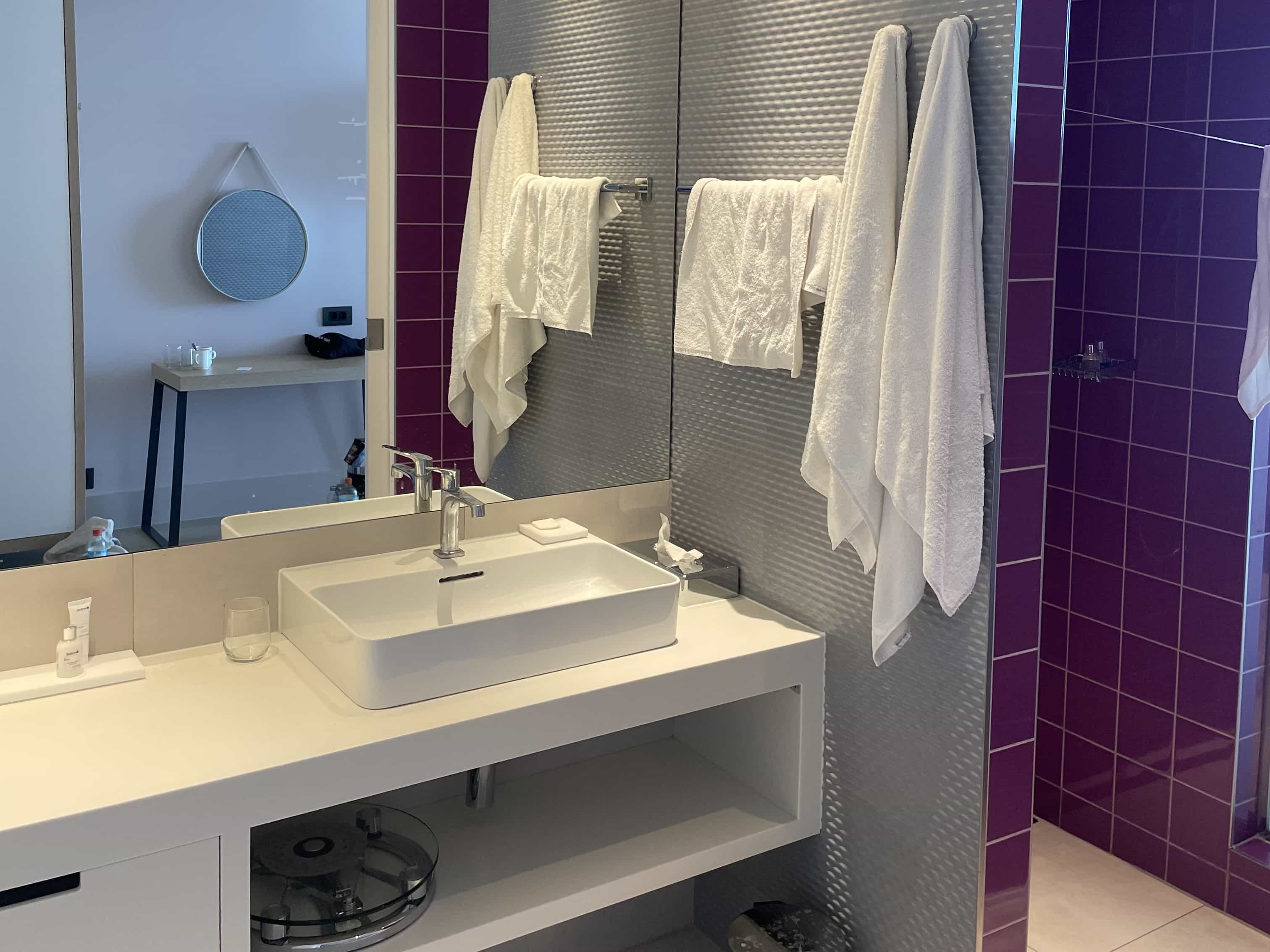 A bathroom countertop with sink and storage, and a shower space to the side