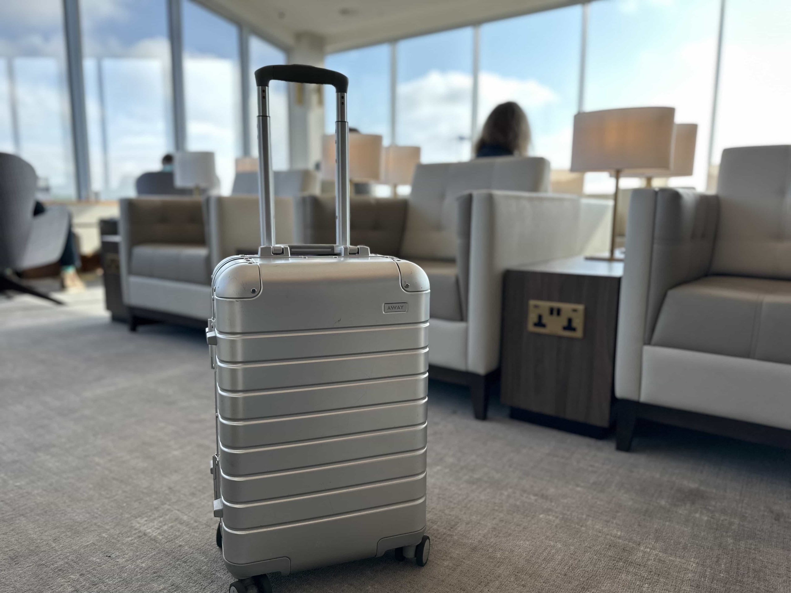 A suitcase situated in the middle of an aisle of armchairs in an airport lounge