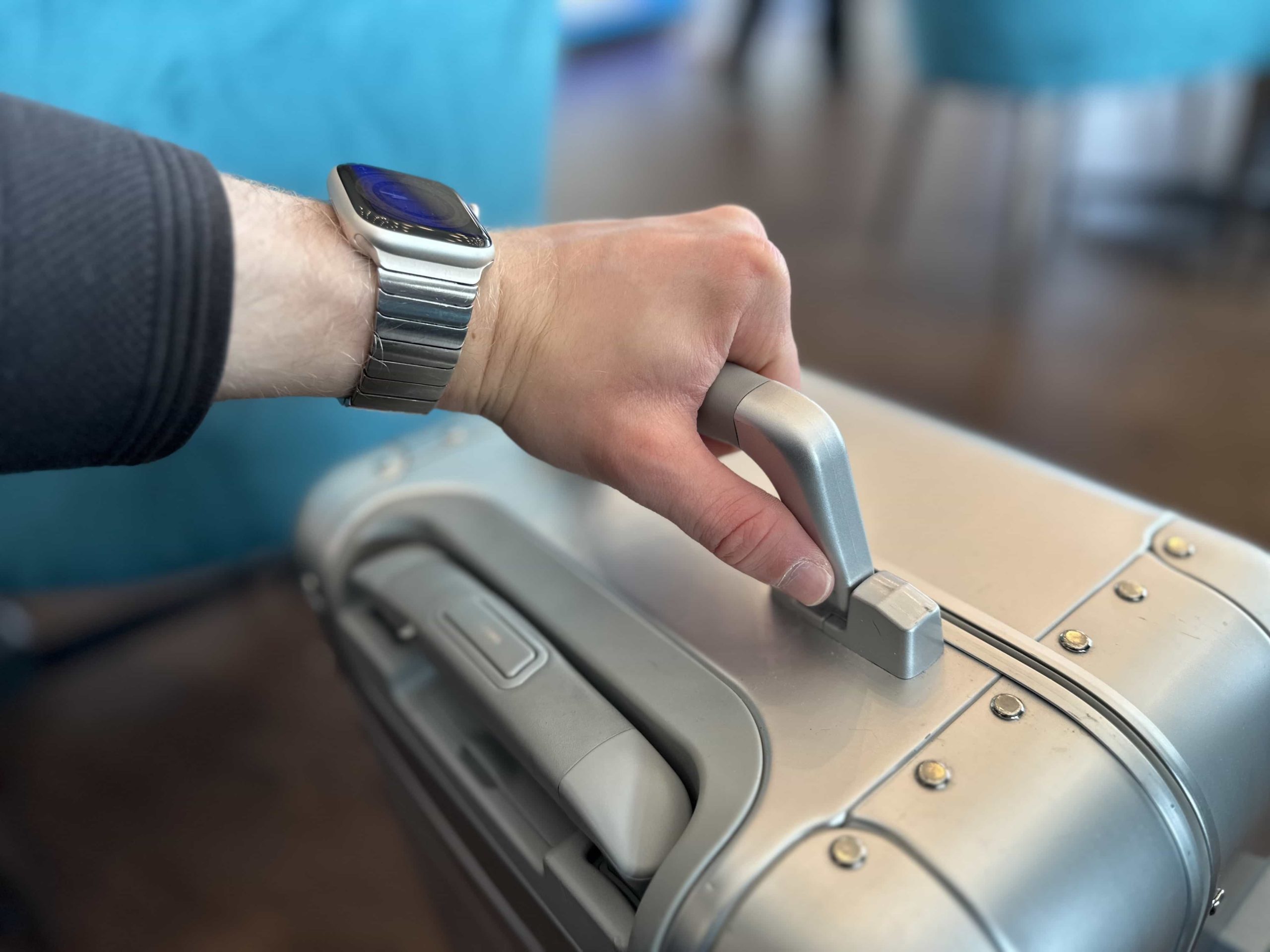 A hand grasping the top handle of a suitcase