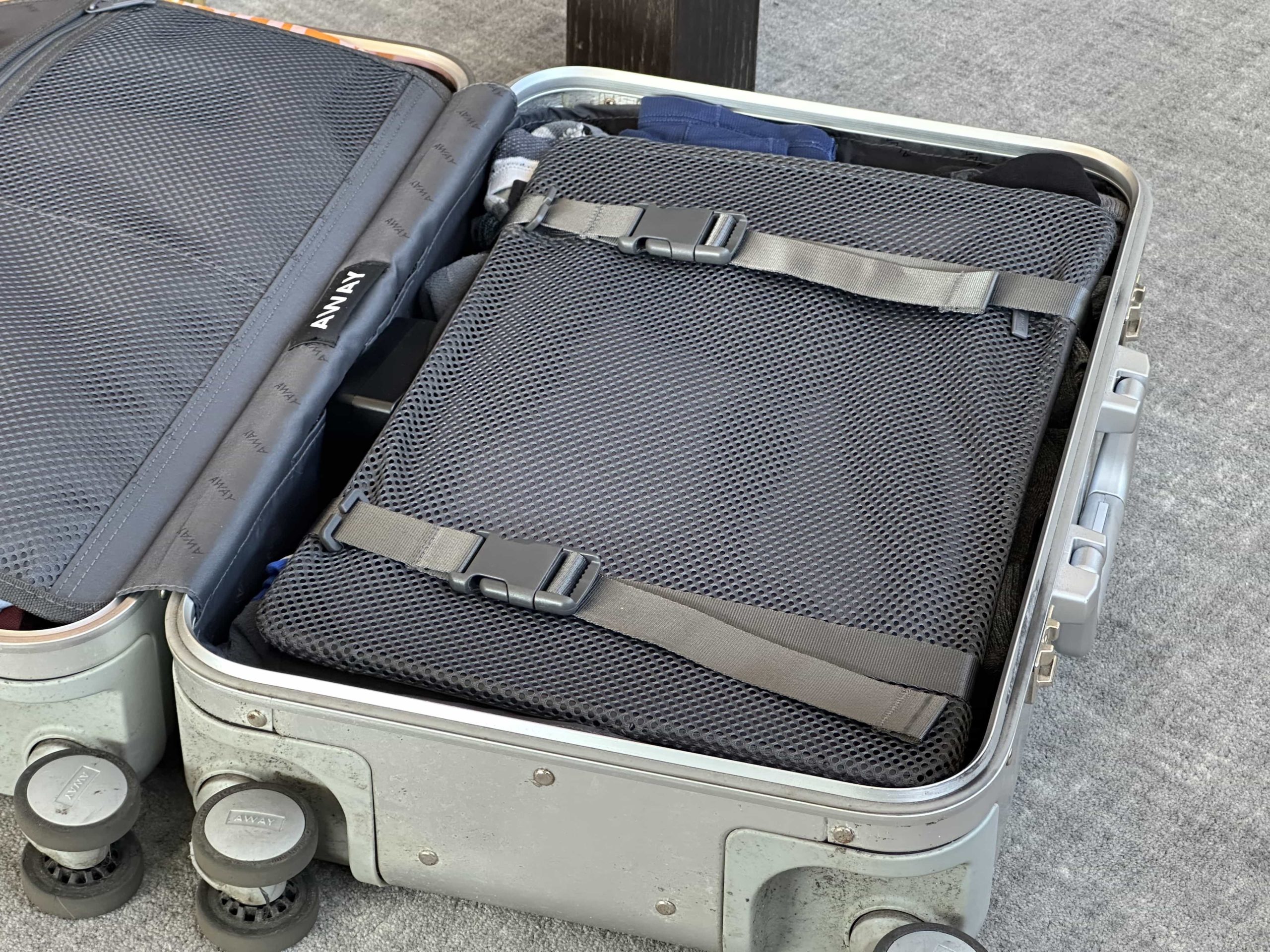 An open suitcase, with a compression layer over the top of packed clothes