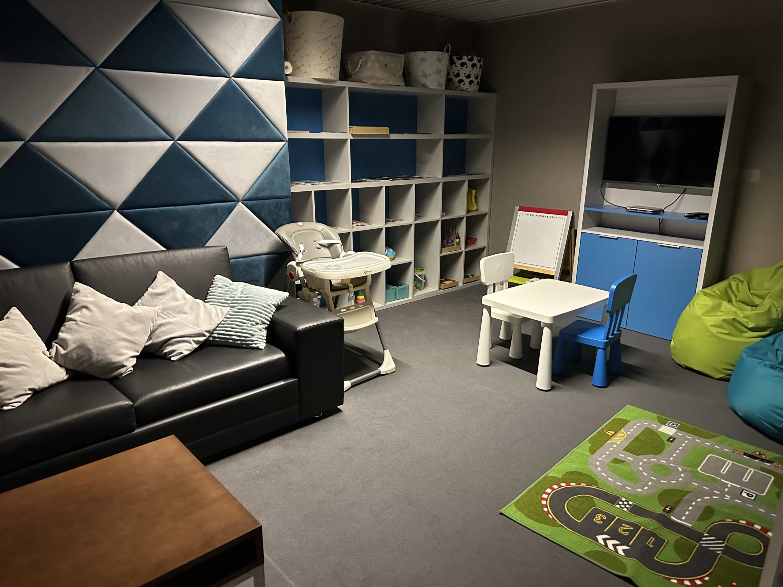 A dimly-lit children's playroom with a sofa, cubby holes, and toys
