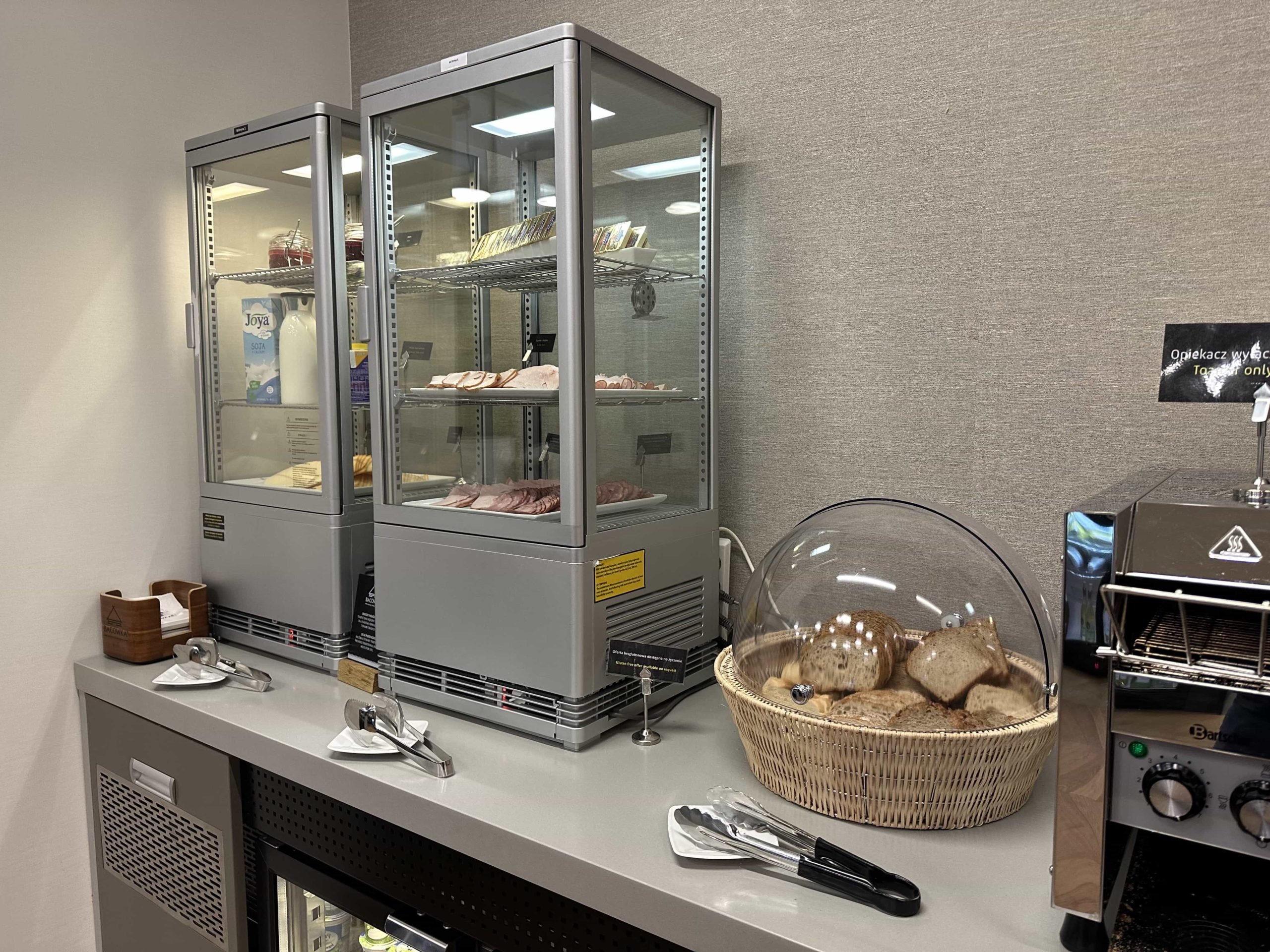 Two fridges with cold cut meats and cheeses, and a basket of bread