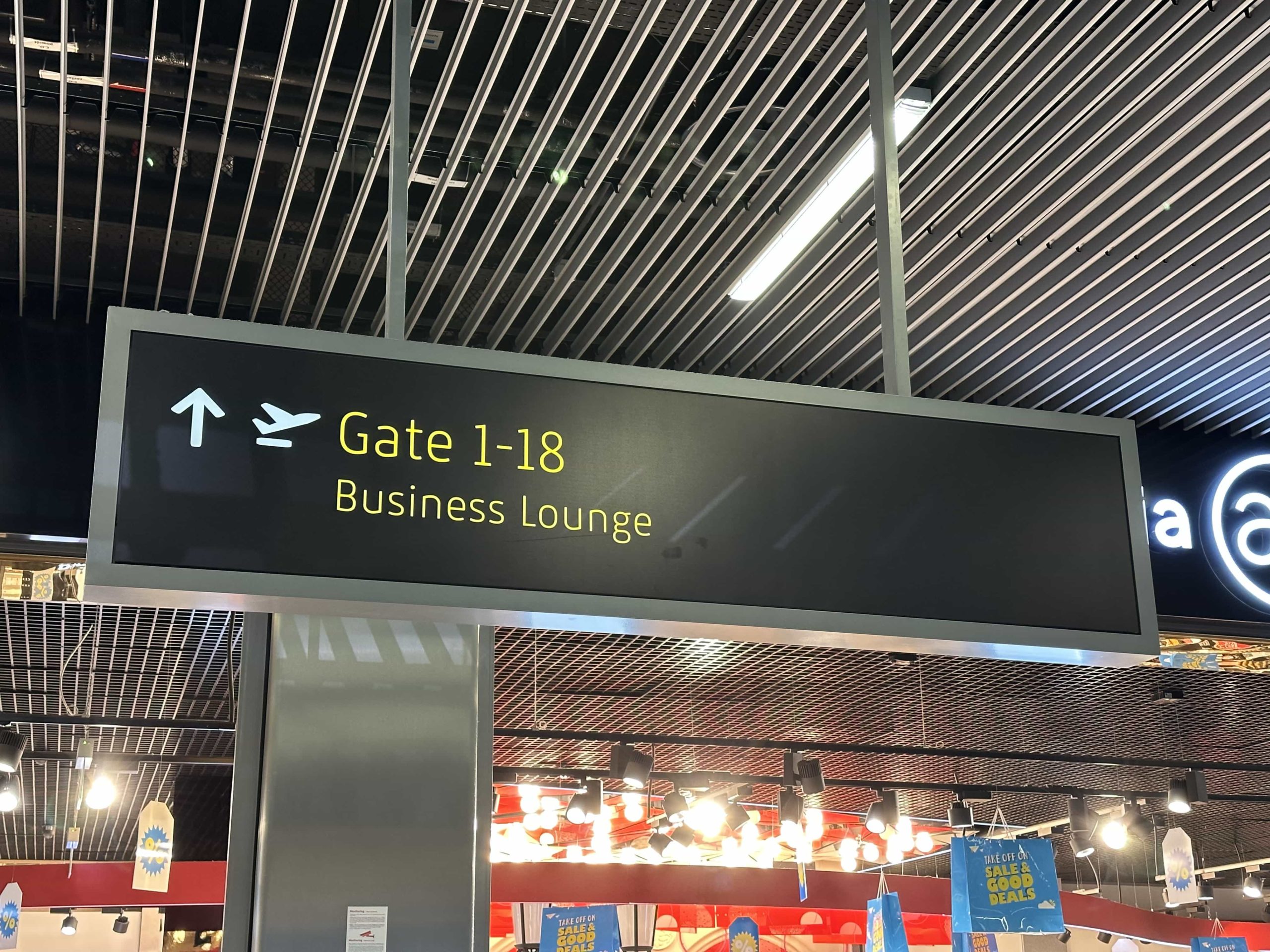 Overhead signage with directions to gates 1 to 18 and a business lounge