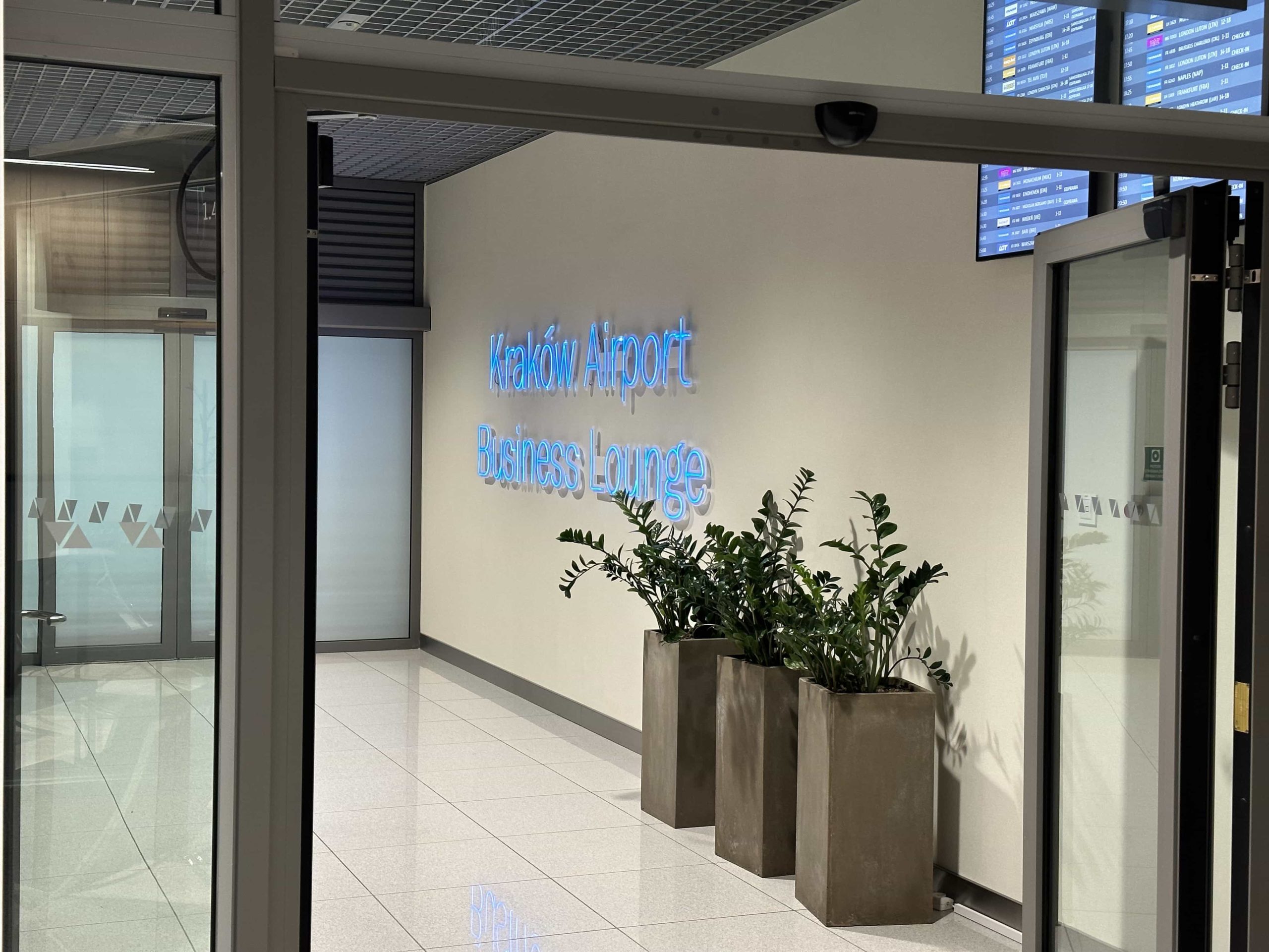 A Kraków Airport Business Lounge neon sign, mounted on a wall at the entrance to a lounge