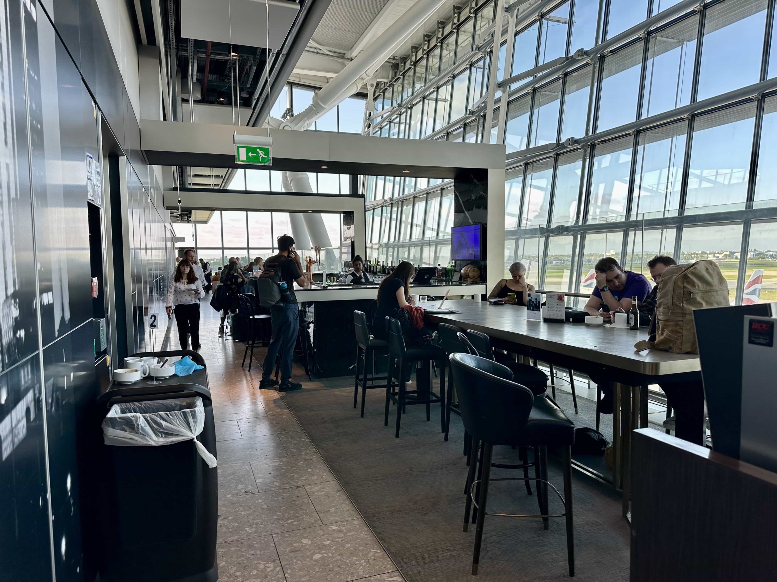 An island-style workstation/dining area next to a bar in an airport lounge