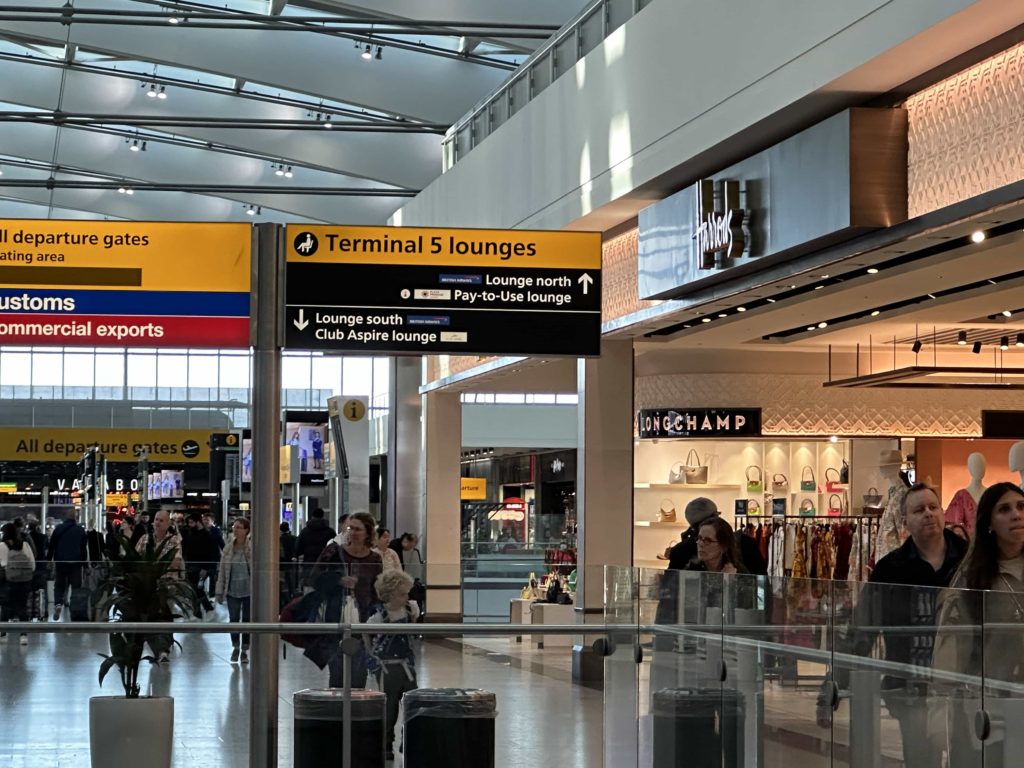 An overhead sign with directions to airport lounges