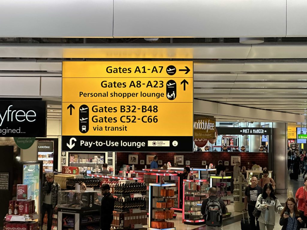 An overhead sign with directions to gates and an airport lounge