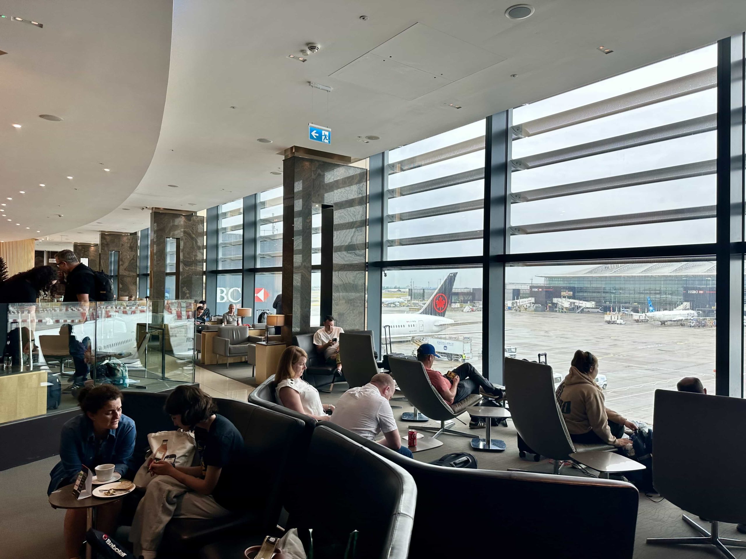 A mixture of sofa seating, and reclinable lounge chairs in front of floor-to-ceiling windows