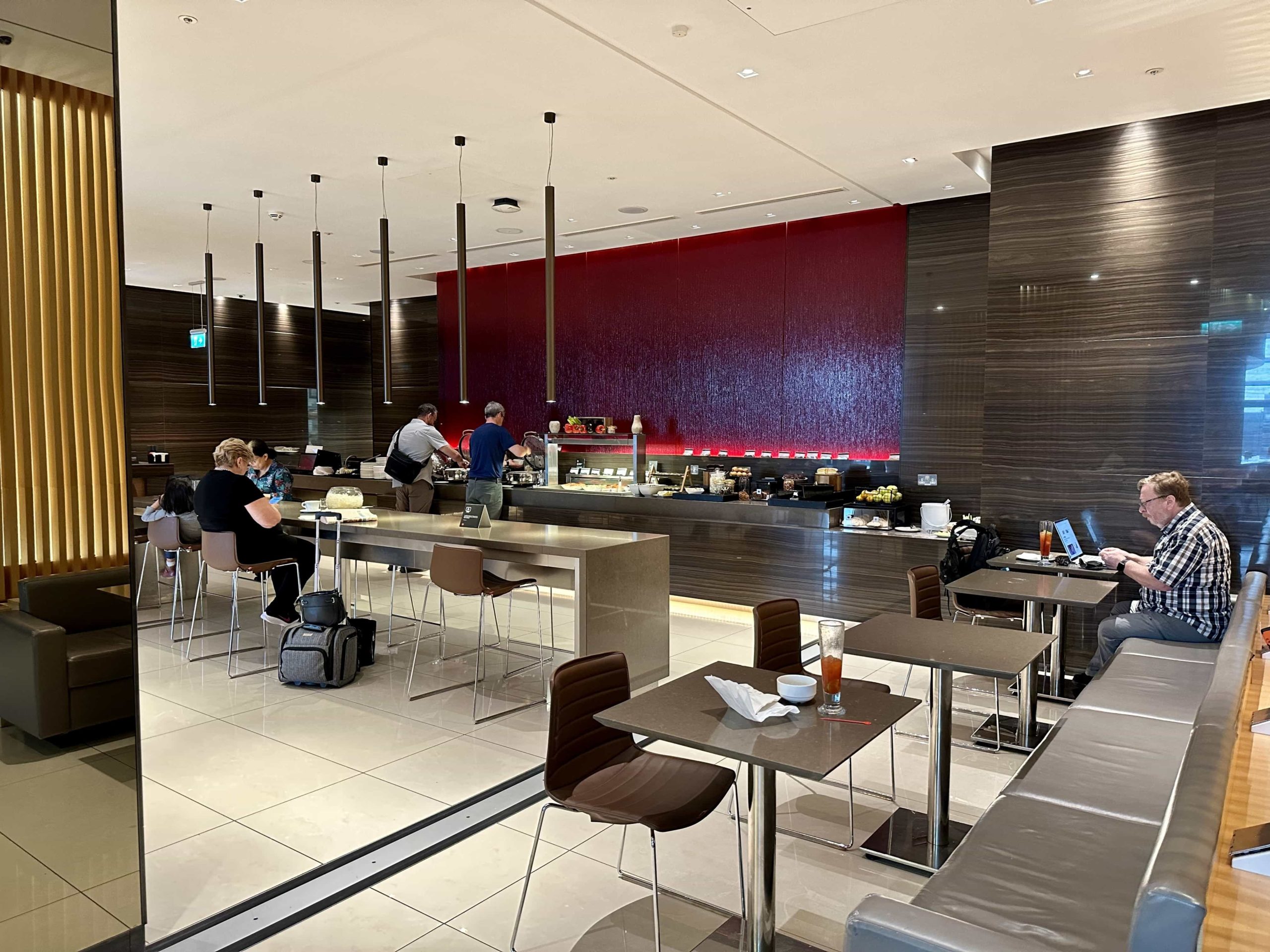 A dining area, with a few dining tables and a communal island. Behind those, a buffet setup