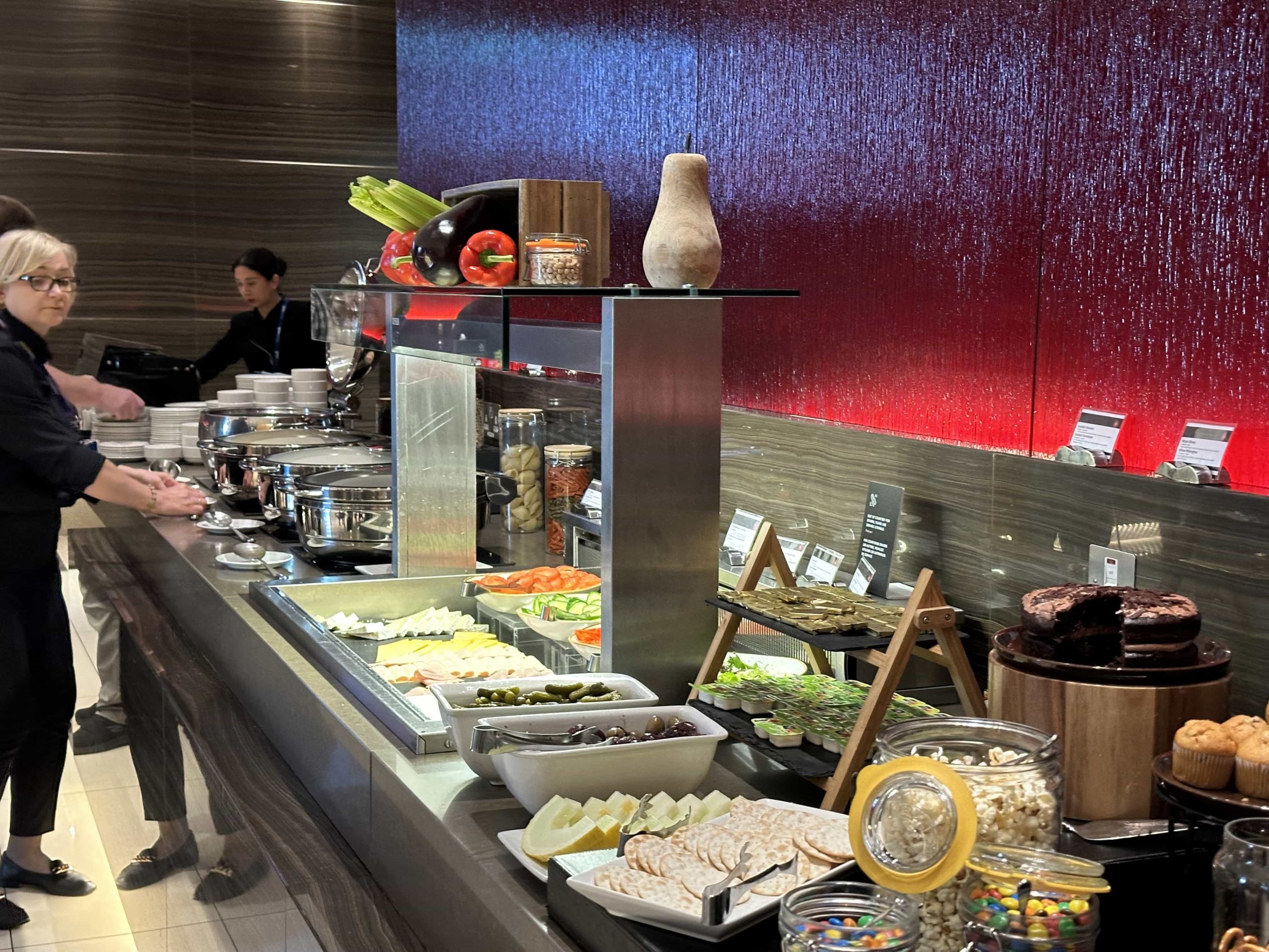 A buffet setup with hot food items, salad options, snacks, and desserts