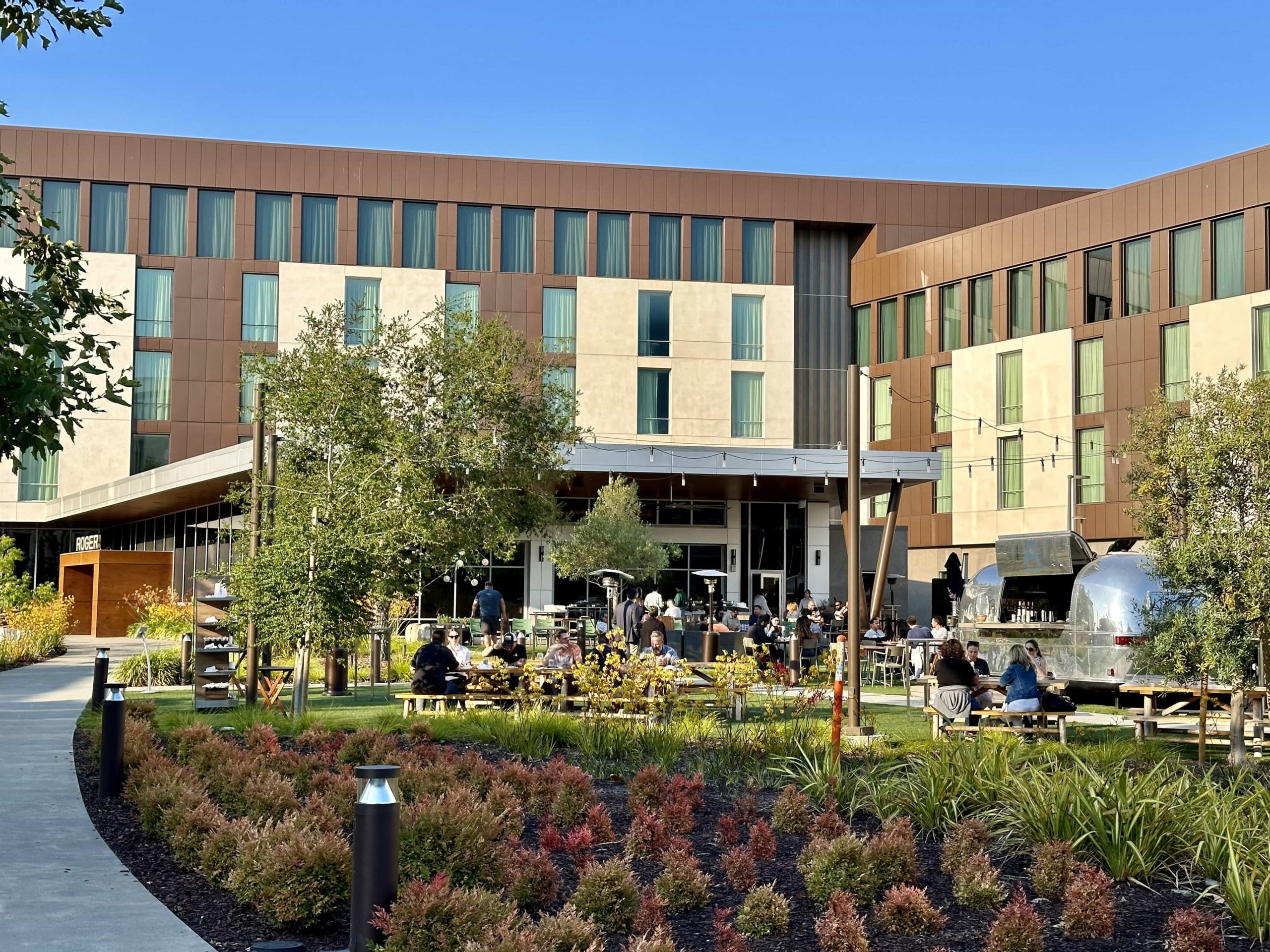 Half paved, half grassy seating area in front of a hotel restaurant