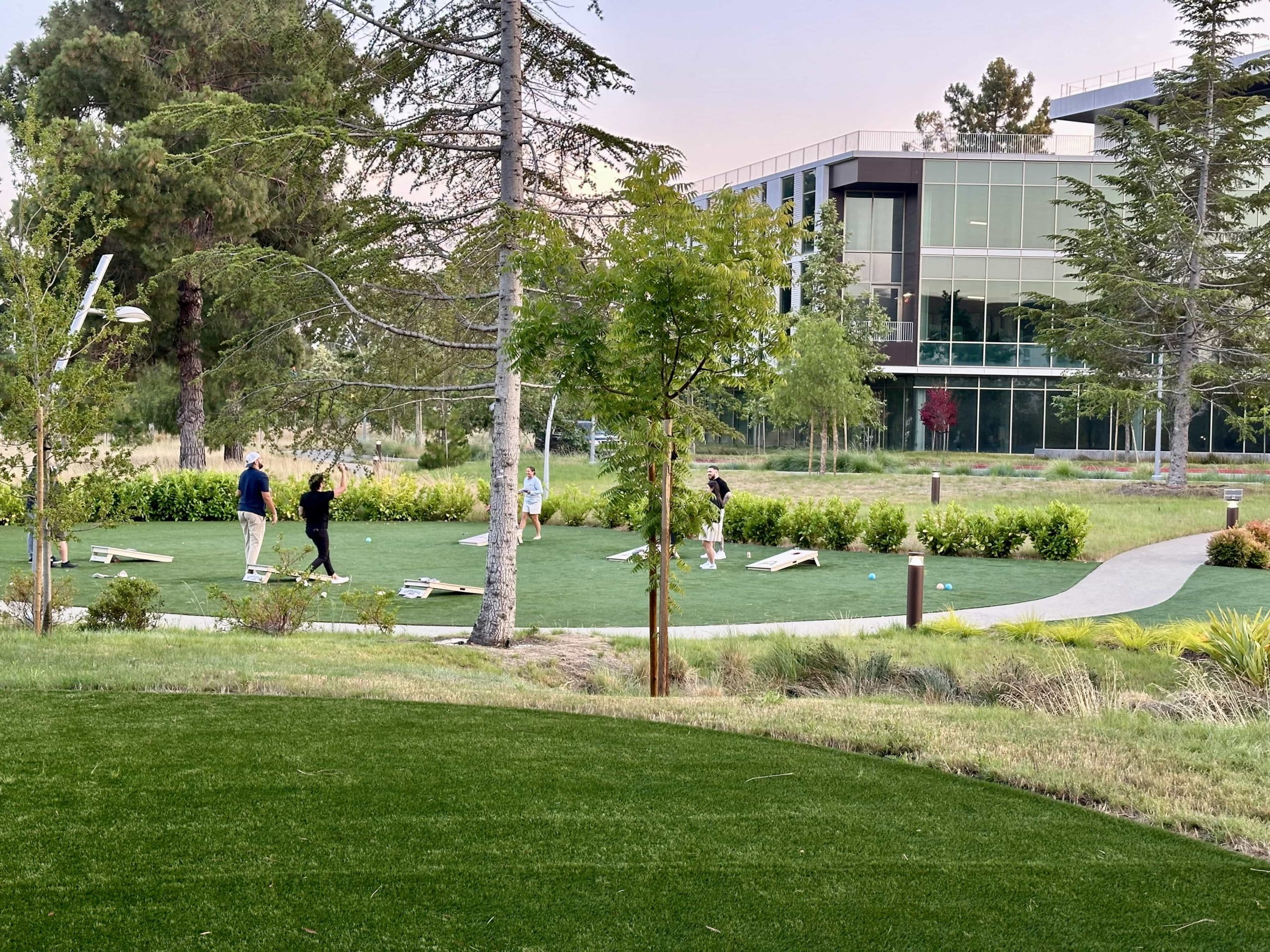 A well-manicured lawn area with people playing shuffleboard games