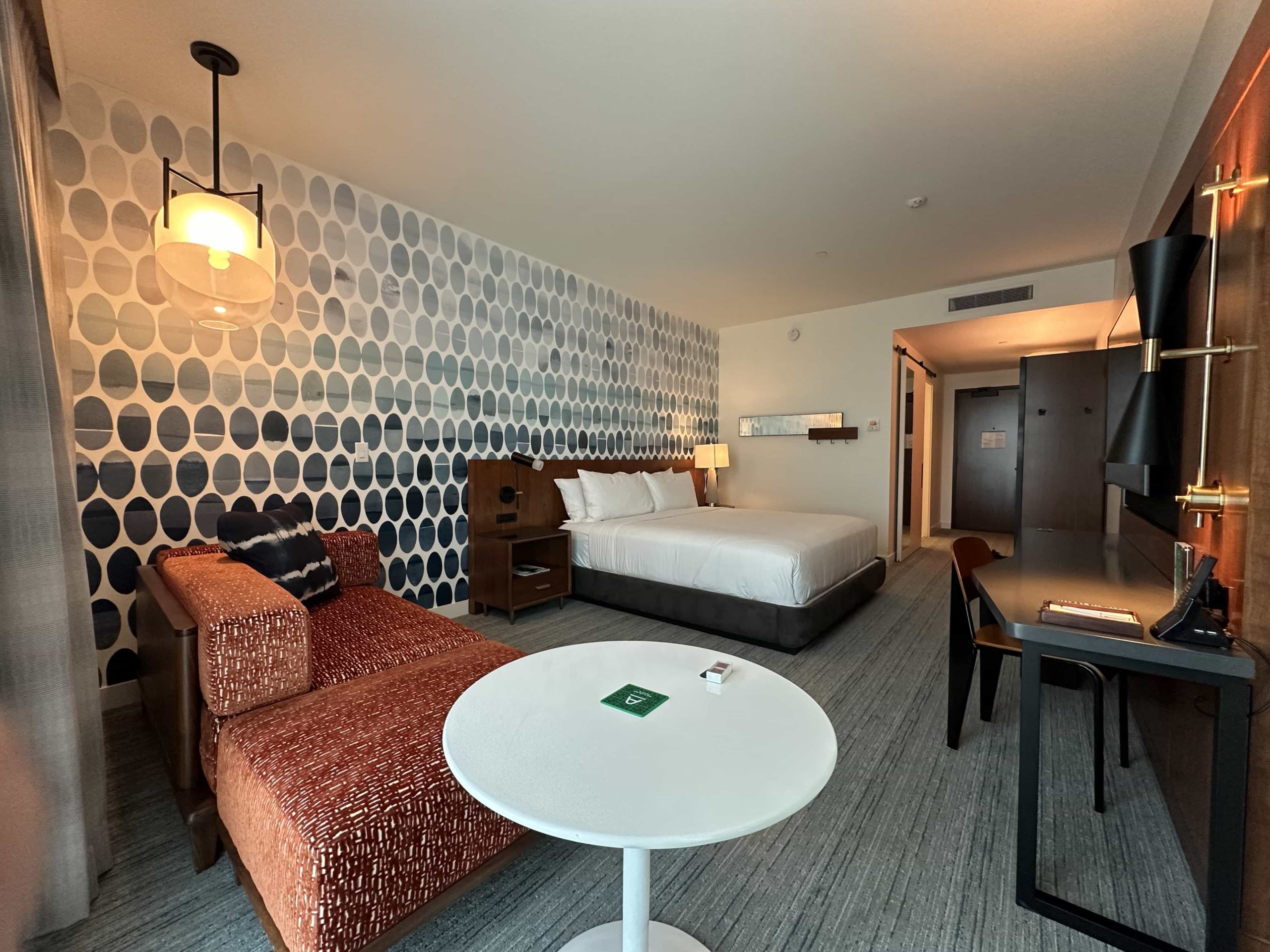 A hotel room with bold wallpaper, a large king-size bed, and modern furnishings