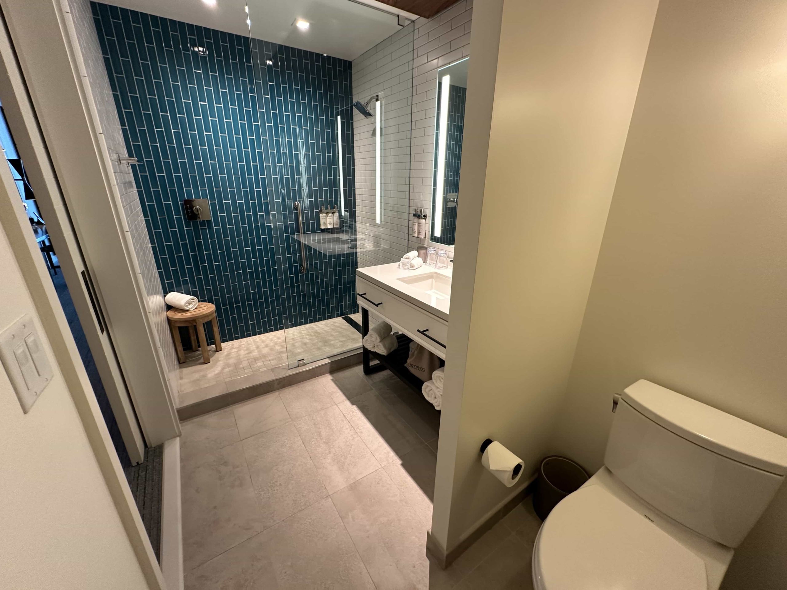 A bright, open-plan bathroom with a vibrant blue accent wall