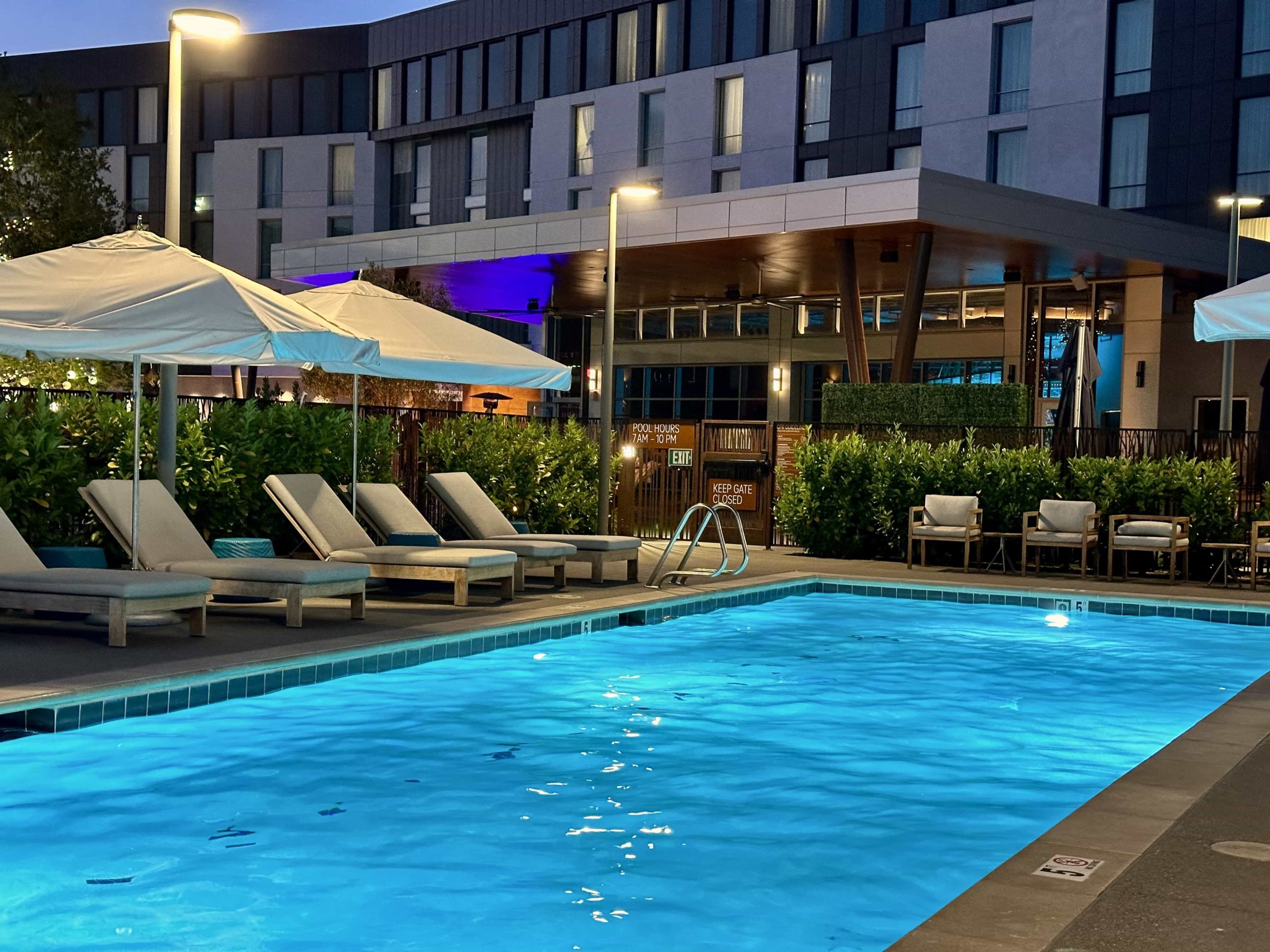 An evening shot of an illuminated pool, surrounded by loungers and umbrellas