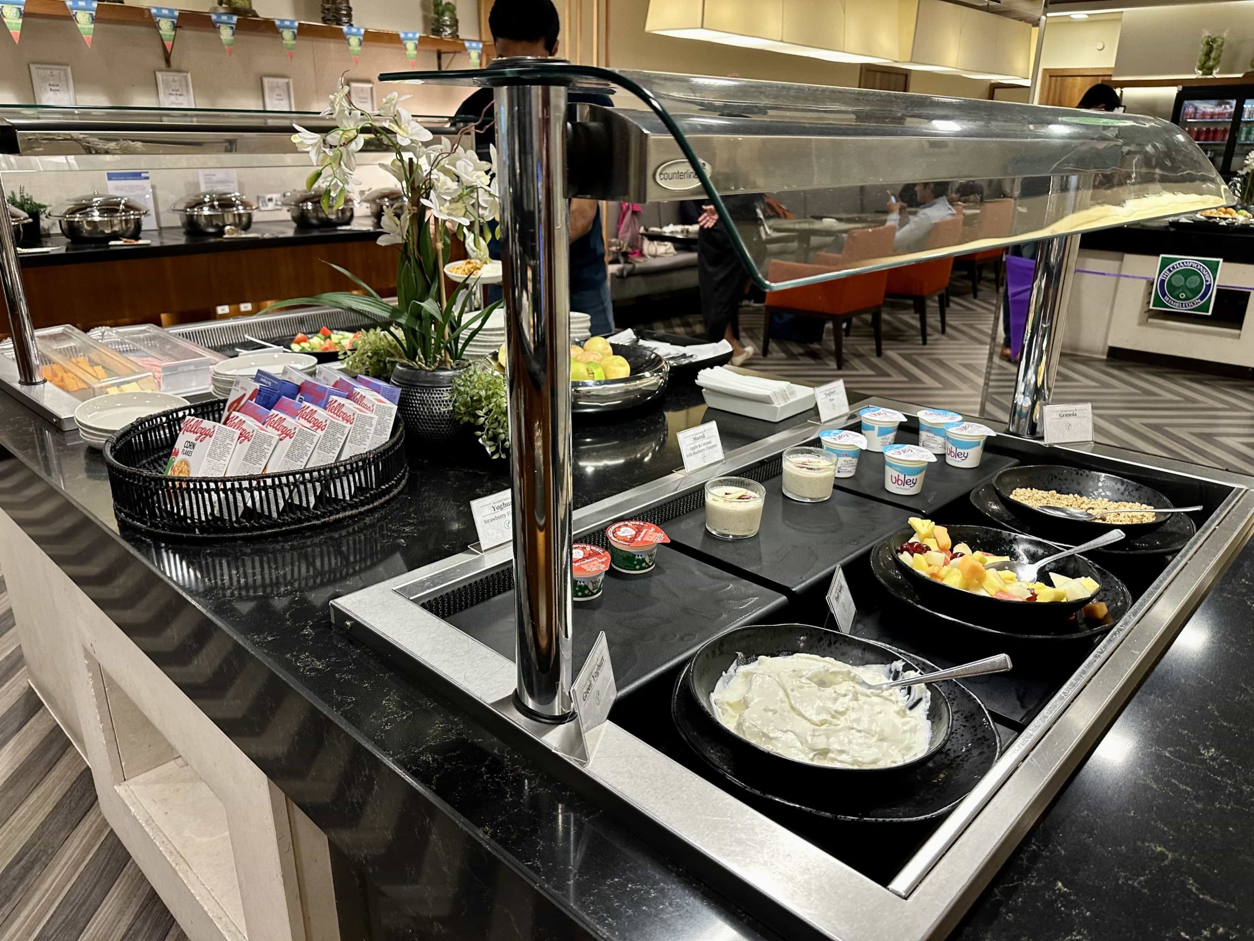 A continental food area in a buffet setup with yogurt, fruit, granola, and more