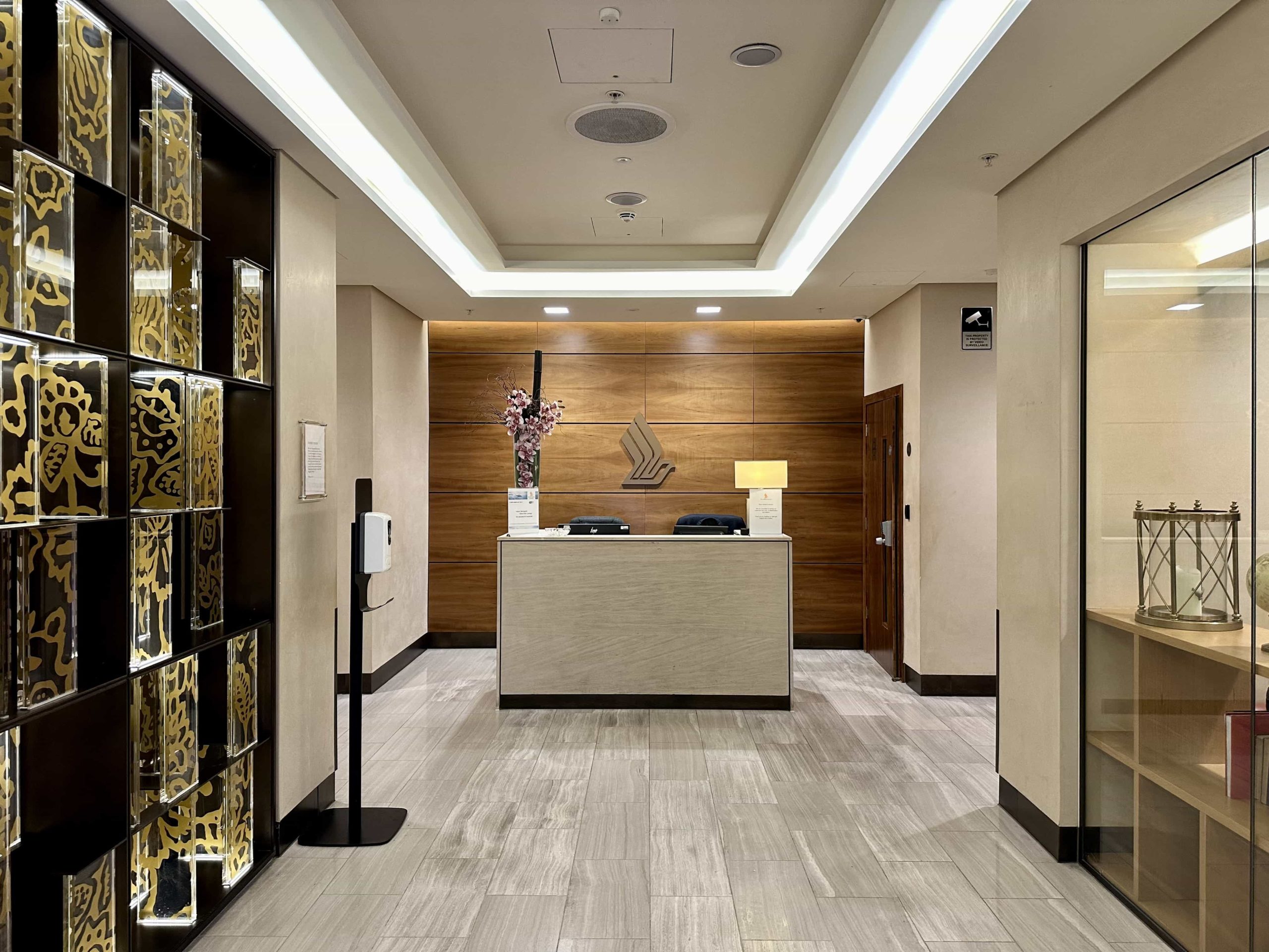 A small reception desk within a lobby area, with Singapore Airlines' signature batik design screen present on the left